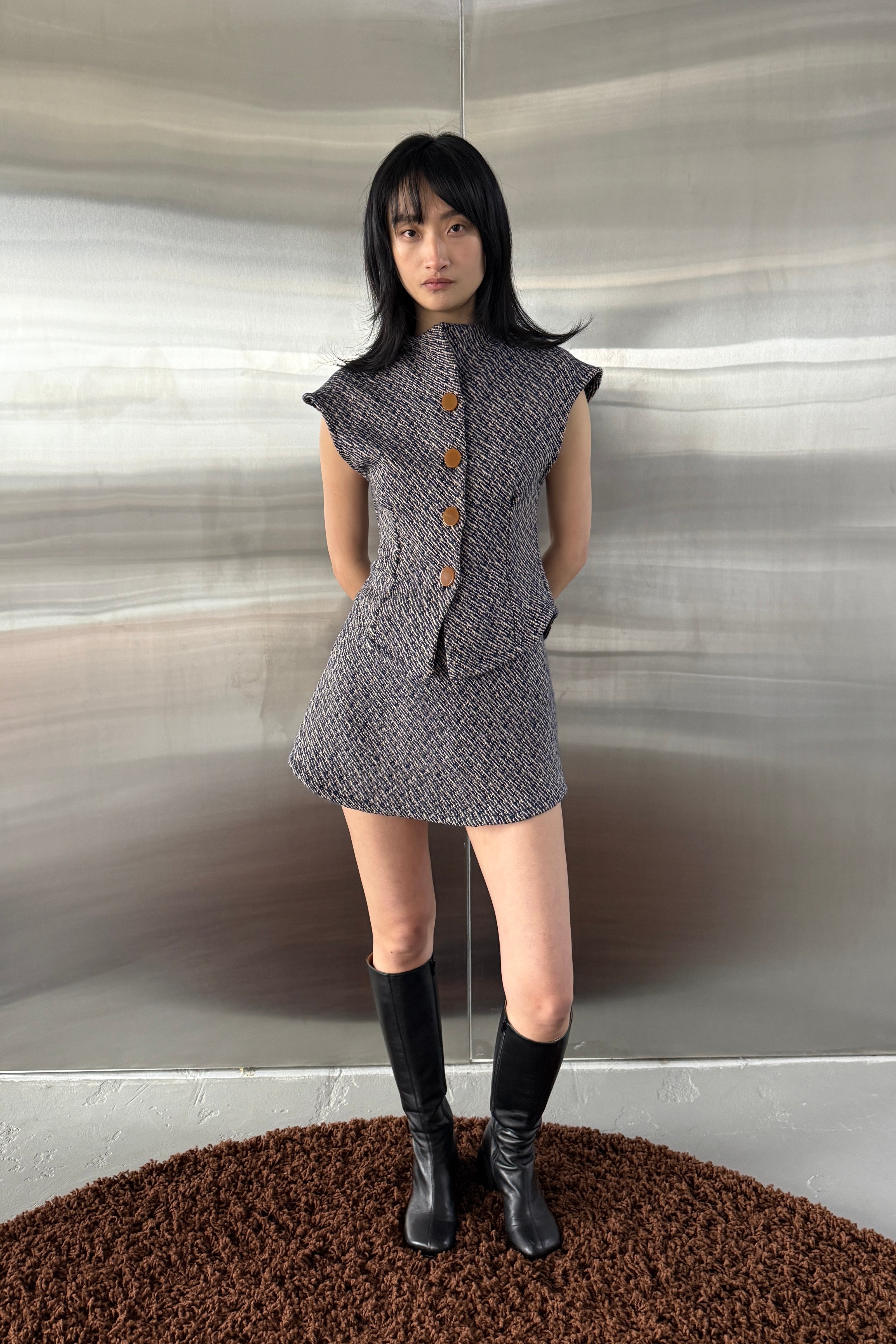 Woman in navy bouclé a-line mini skirt. Styled with matching cap sleeve jacket.