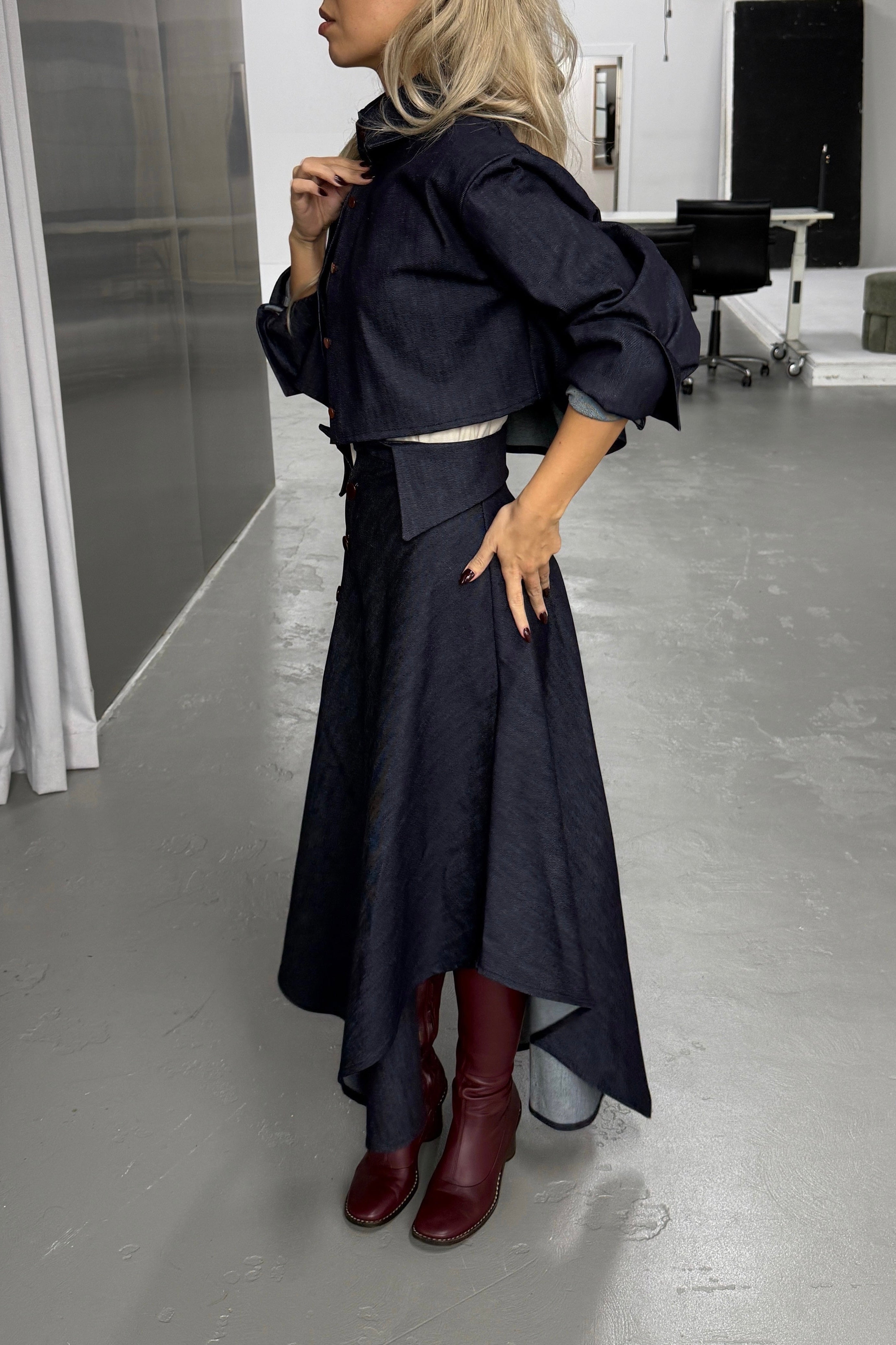 Woman in denim handkerchief hem long skirt with collar waist band detail. Styled with matching boxy cropped jacket.