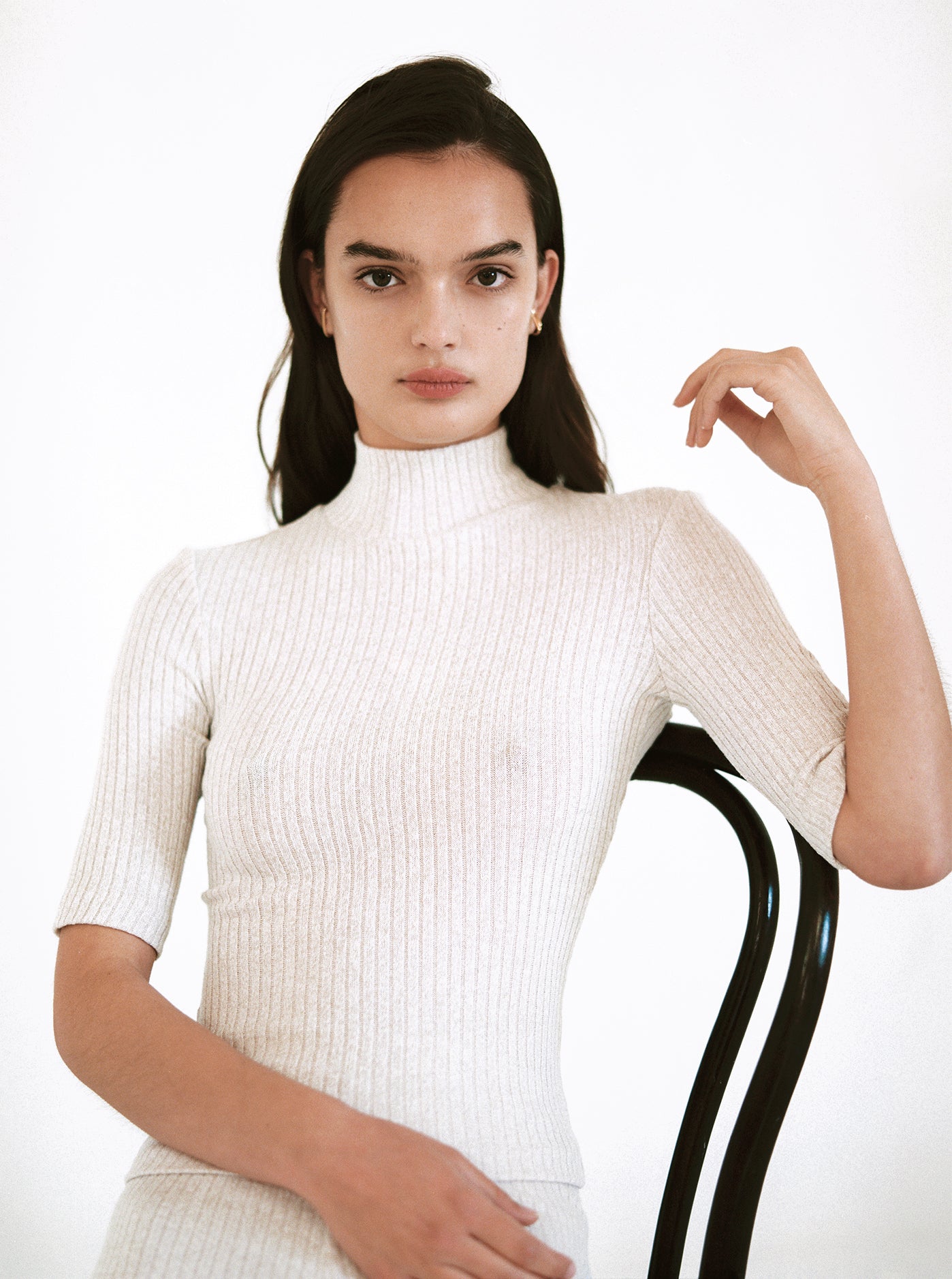 Woman in Oat rib knit turtle neck with half length sleeves.