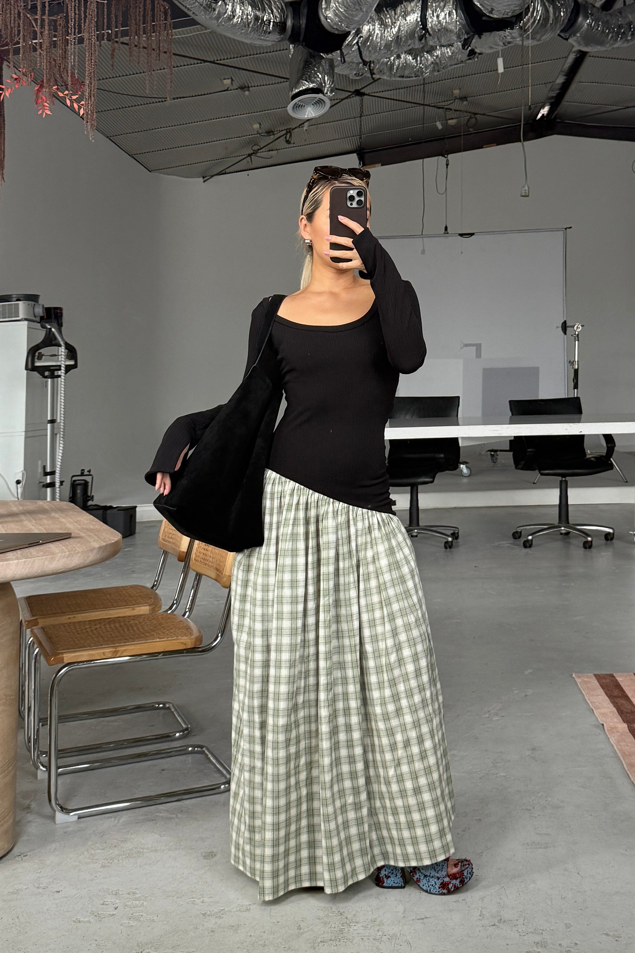 Woman in long sleeve black dress, with extra long sleeves, scooped neckline, and artfully gathered green plaid skirt. Top flatters the figure whilst the skirt flows with every movement. Can be dressed up or down.