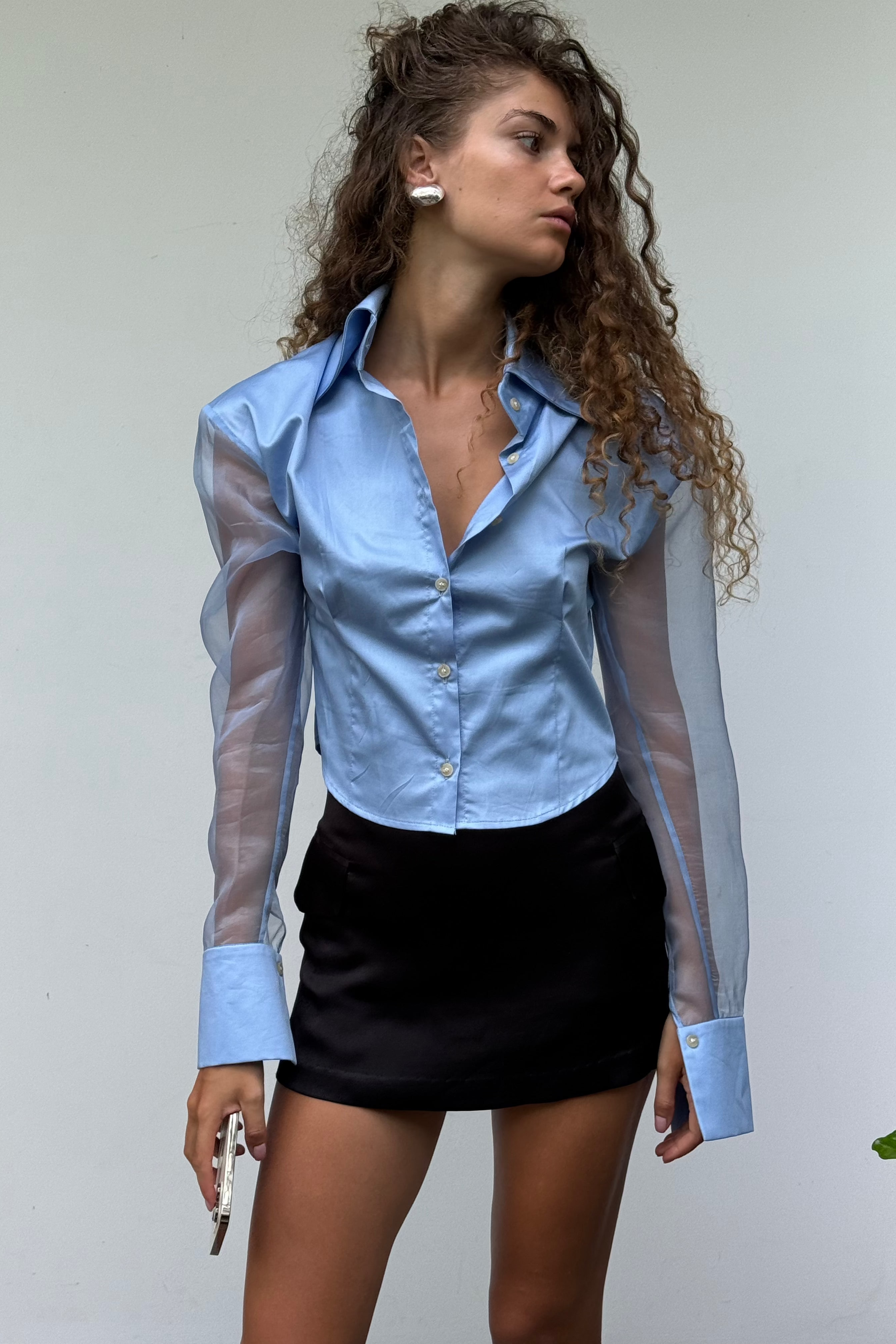 Blue button down shirt with silk organza sheer sleeves. Styled buttoned up with a black mini skirt. Perfect for the office or summer outings.