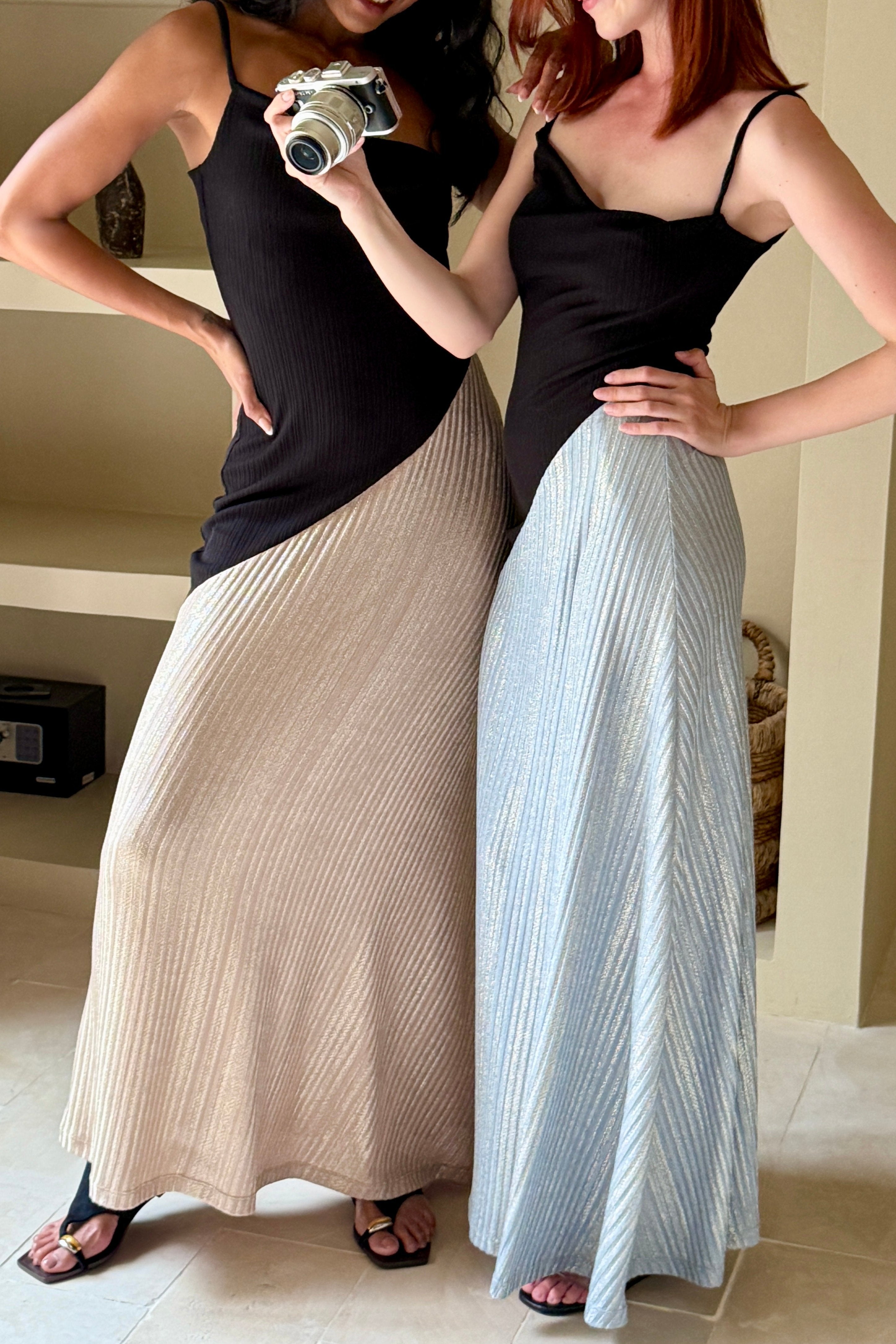 Woman in a long black dress with cowl neck and asymmetric sparkly blue skirt. Spaghetti straps and maxi length. Summer soirée essential.