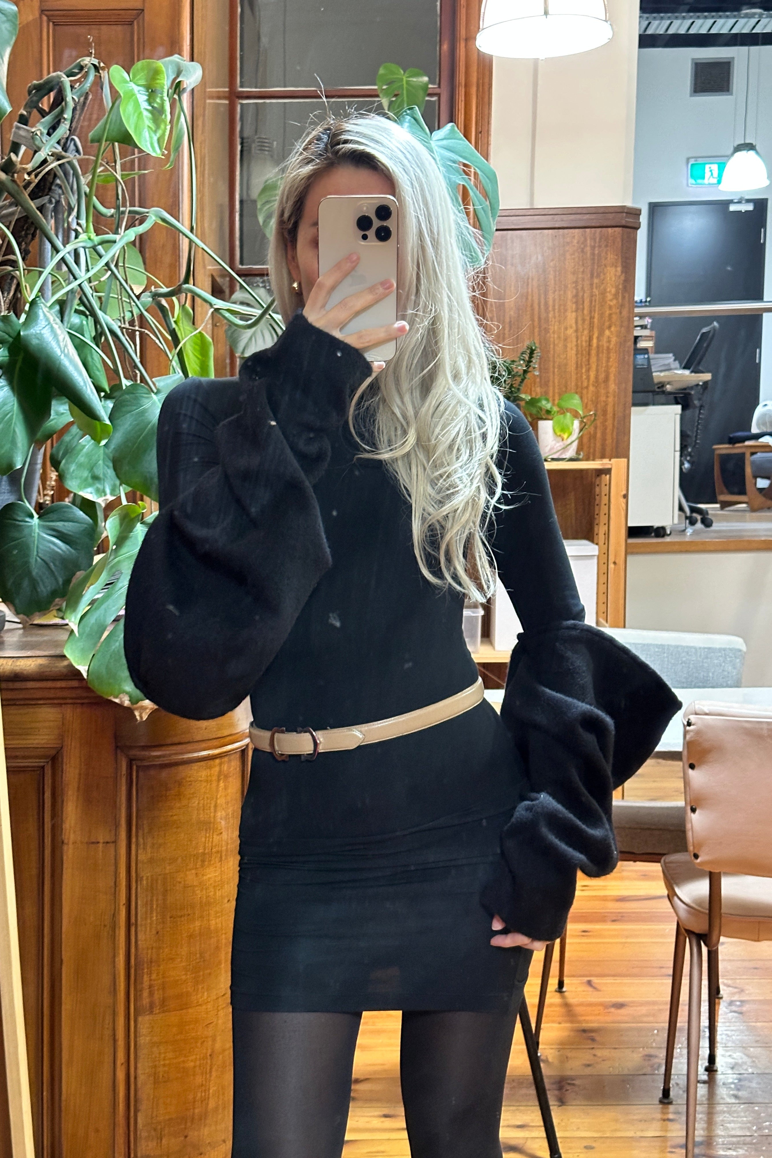 Black turtle neck mini dress, form fitting, with voluminous black arm warmer details. Winter essential. Styled with tights and a beige belt.