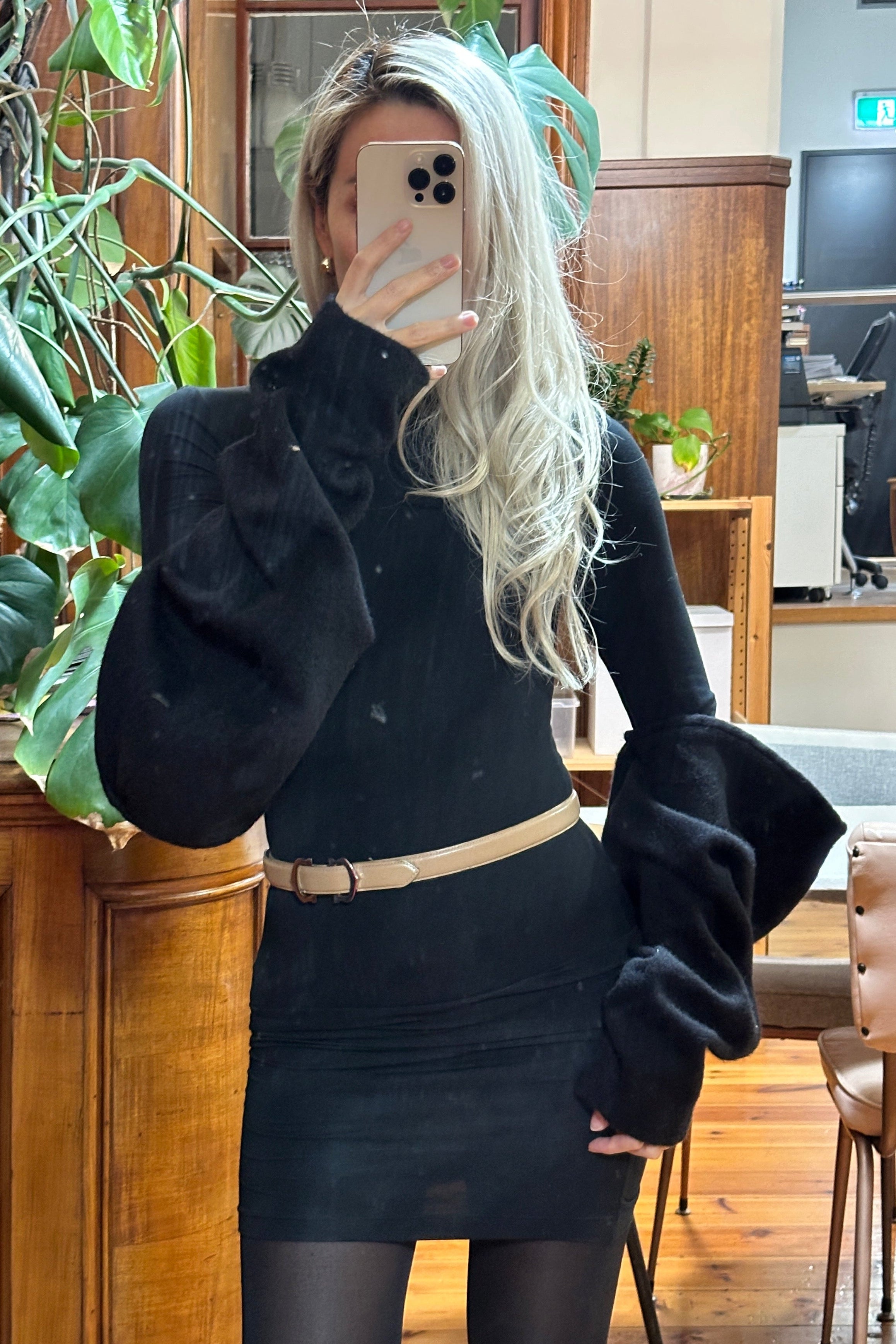 Black turtle neck mini dress, form fitting, with voluminous black arm warmer details. Winter essential. Styled with tights and a beige belt.