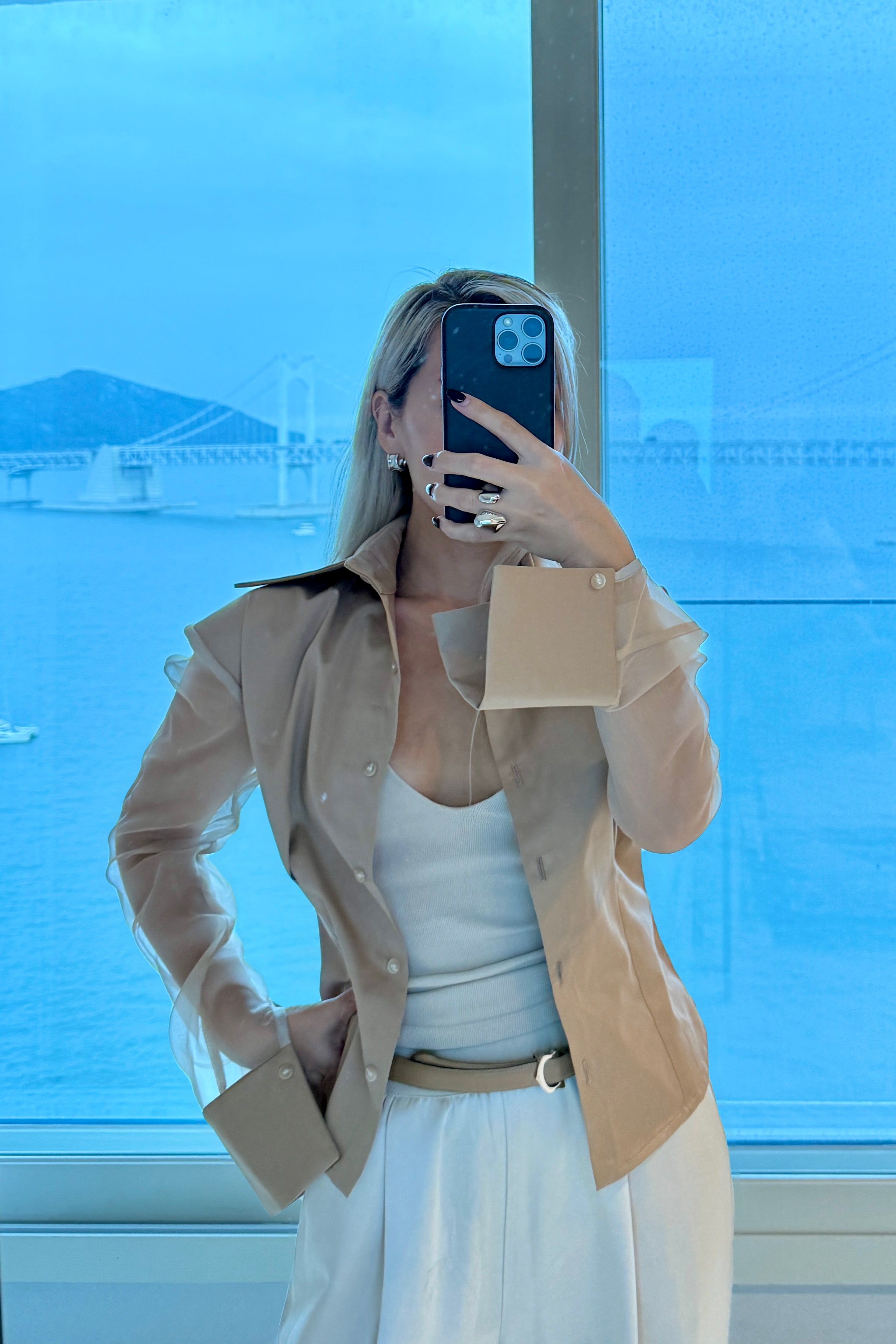 Beige button down shirt with silk organza sheer sleeves. Styled open over a white tank top. Perfect for the office or summer outings.