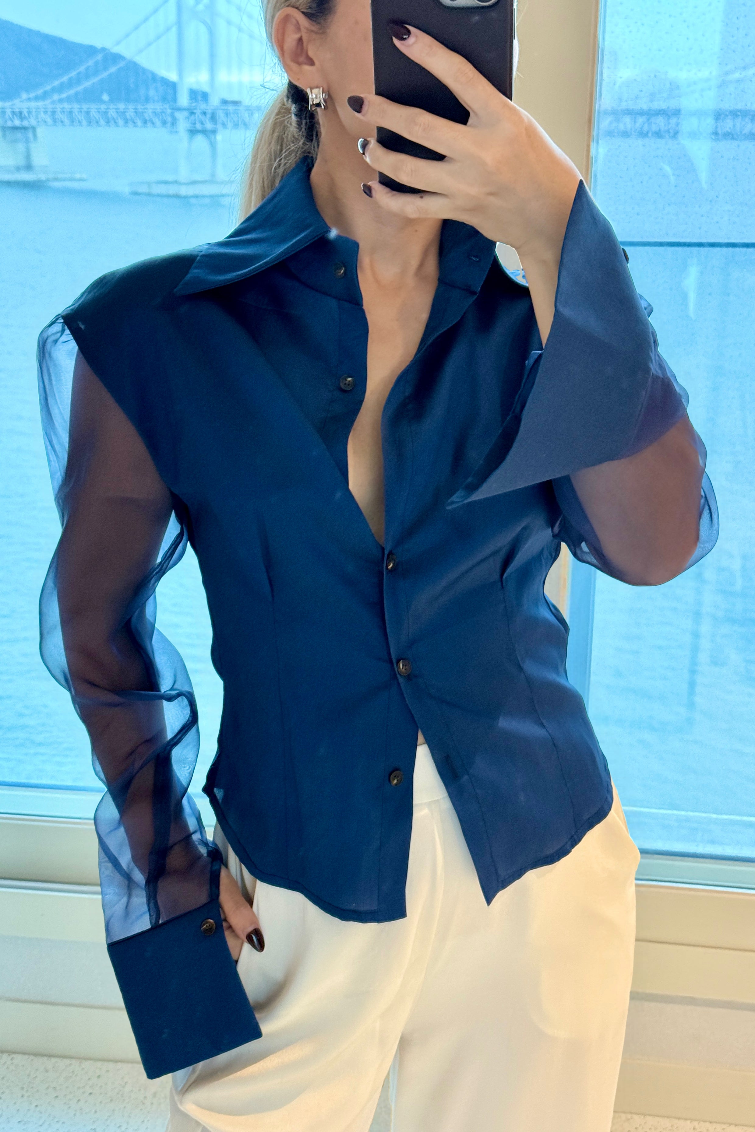 Royal navy blue button down shirt with silk organza sheer sleeves. Styled buttoned up with white pants. Perfect for the office or summer outings.