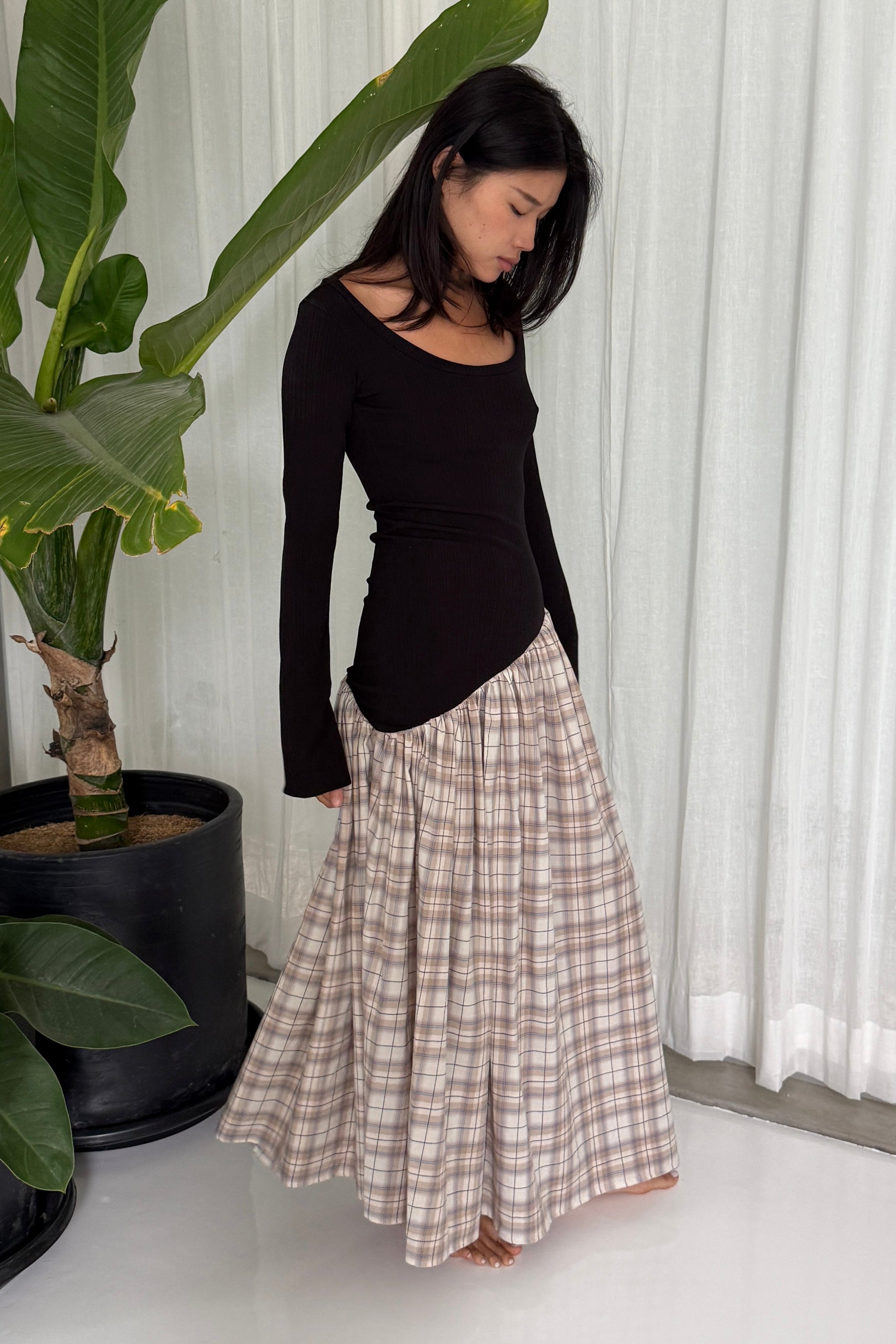Woman in long sleeve dress, with extra long sleeves, scooped neckline, and artfully gathered plaid skirt. Top flatters the figure whilst the skirt flows with every movement. Can be dressed up or down.
