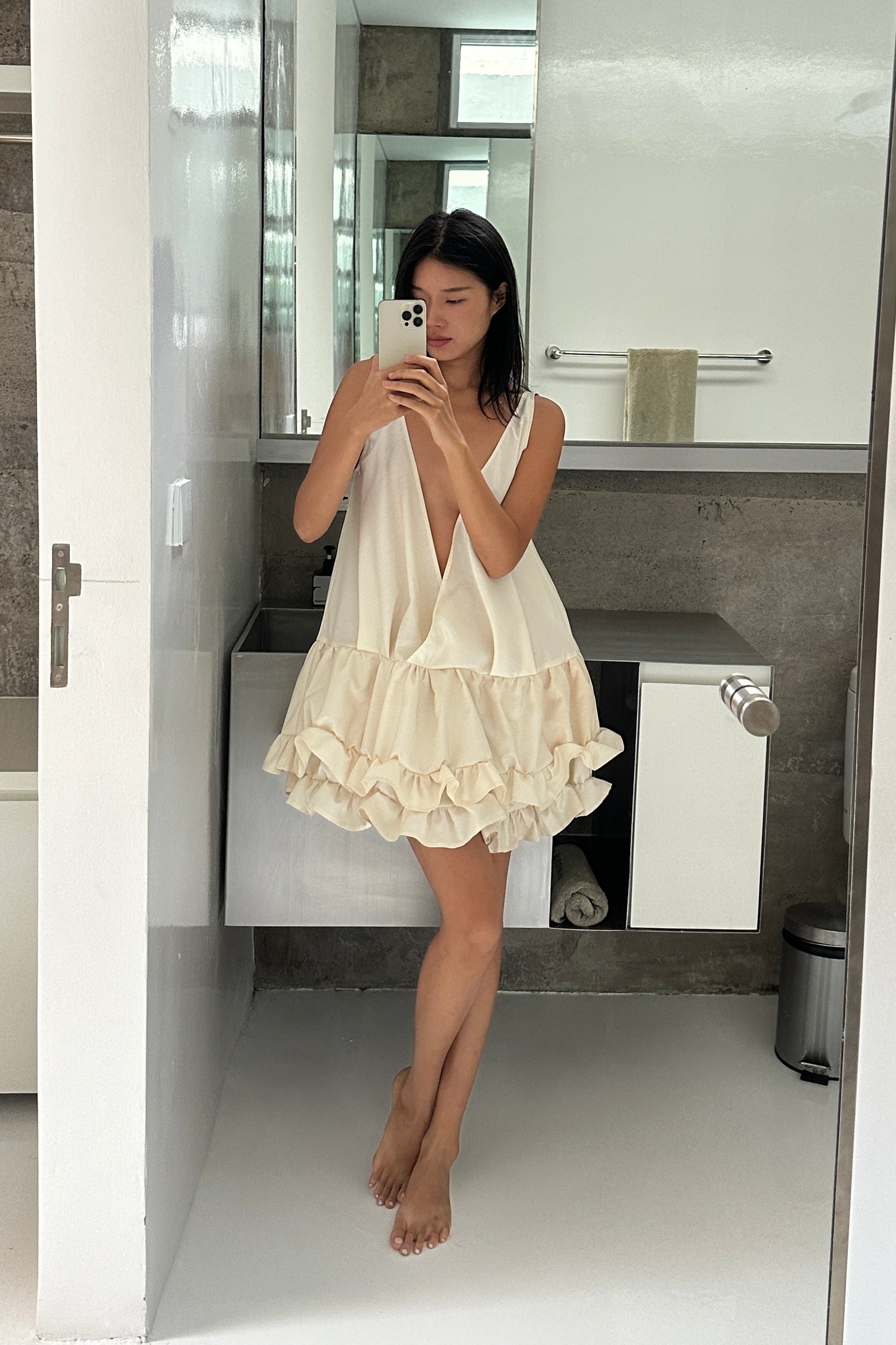 Woman in a cream deep v-neck mini ruffled dress. The perfect beach cover up or casual summer dress.
