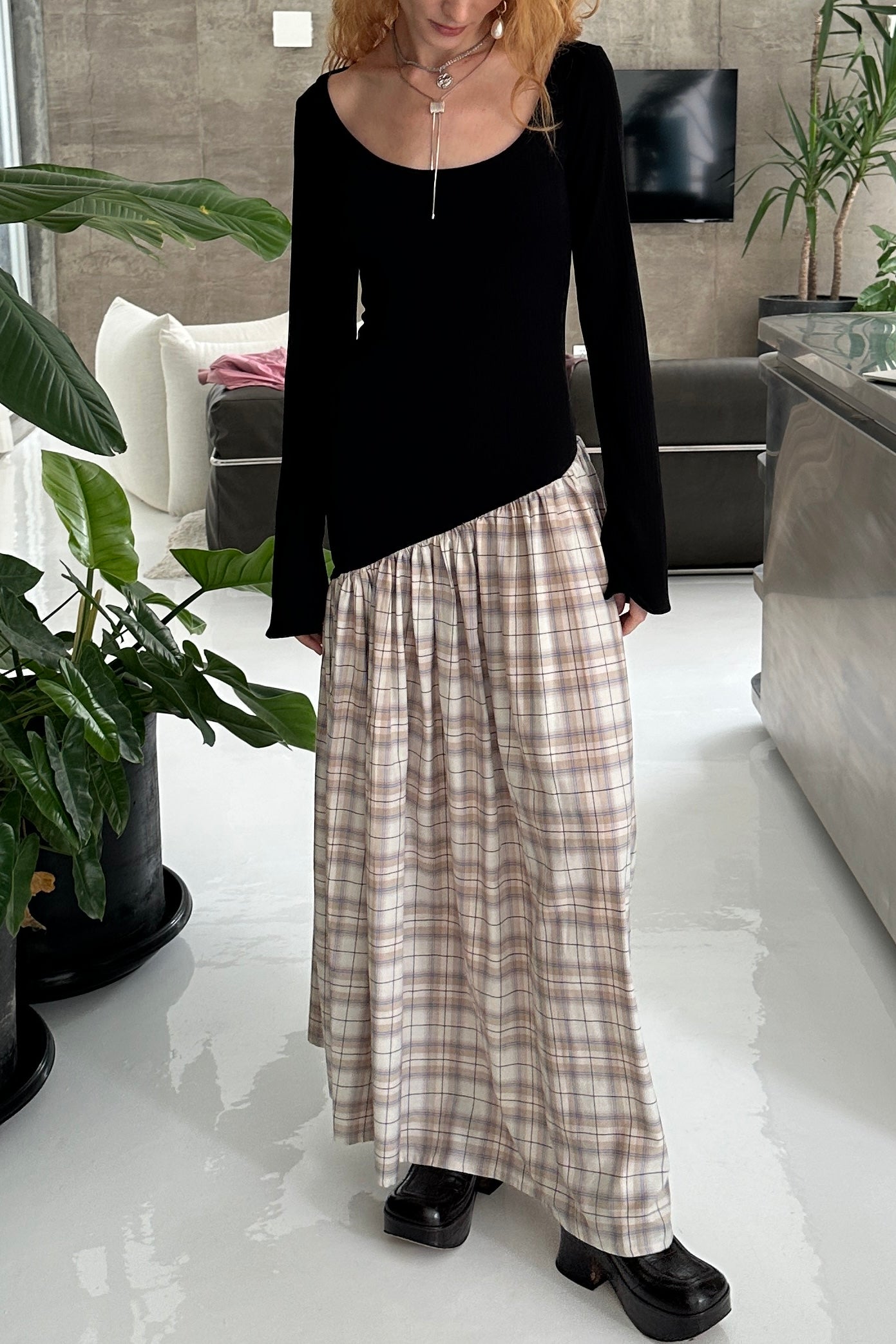 Woman in long sleeve dress, with extra long sleeves, scooped neckline, and artfully gathered plaid skirt. Top flatters the figure whilst the skirt flows with every movement. Can be dressed up or down. Paired with two silver necklaces.