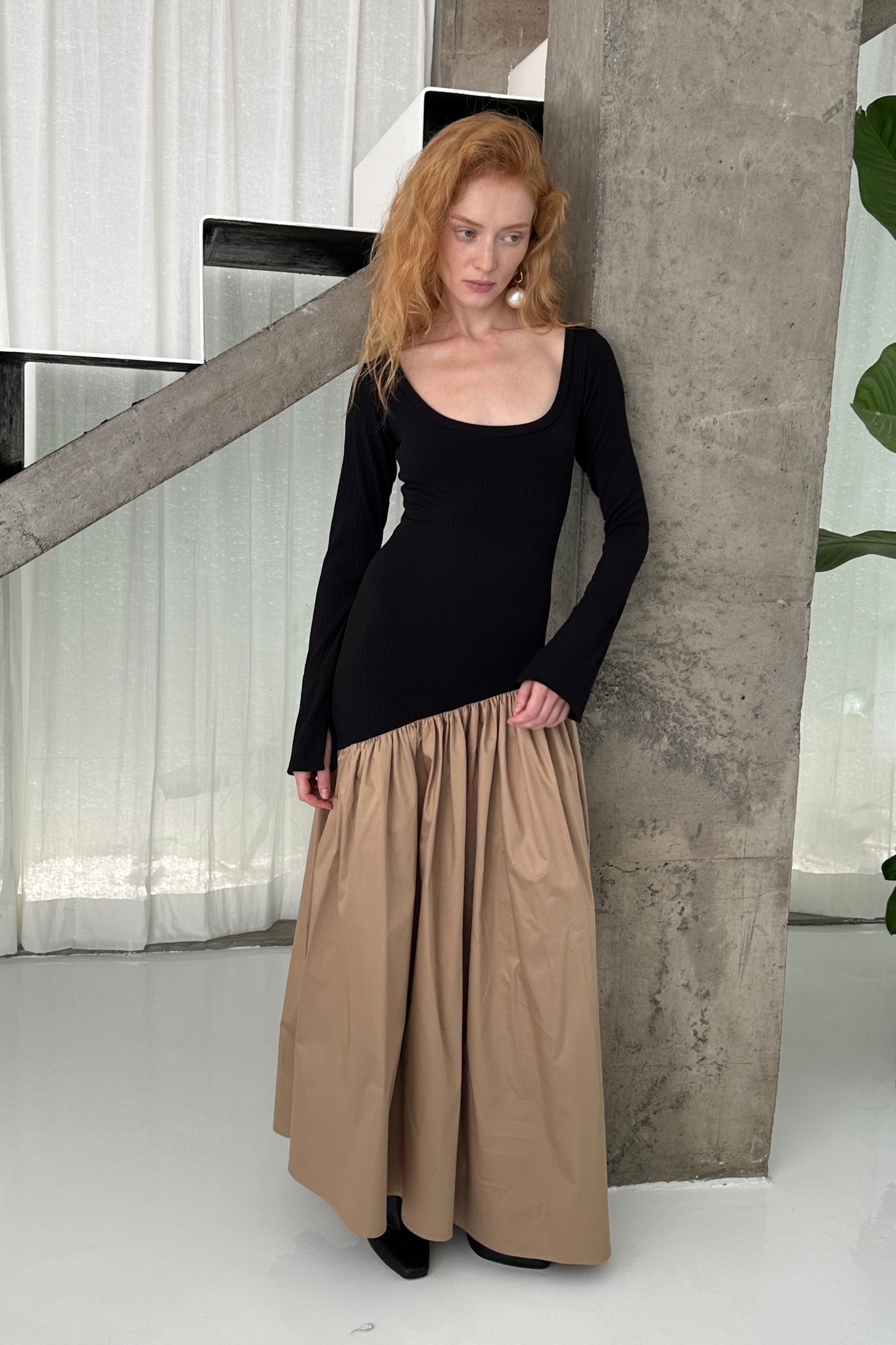 Woman in long sleeve dress, with extra long sleeves, scooped neckline, and artfully gathered asymmetric beige skirt. Top flatters the figure whilst the skirt flows with every movement. Can be dressed up or down.