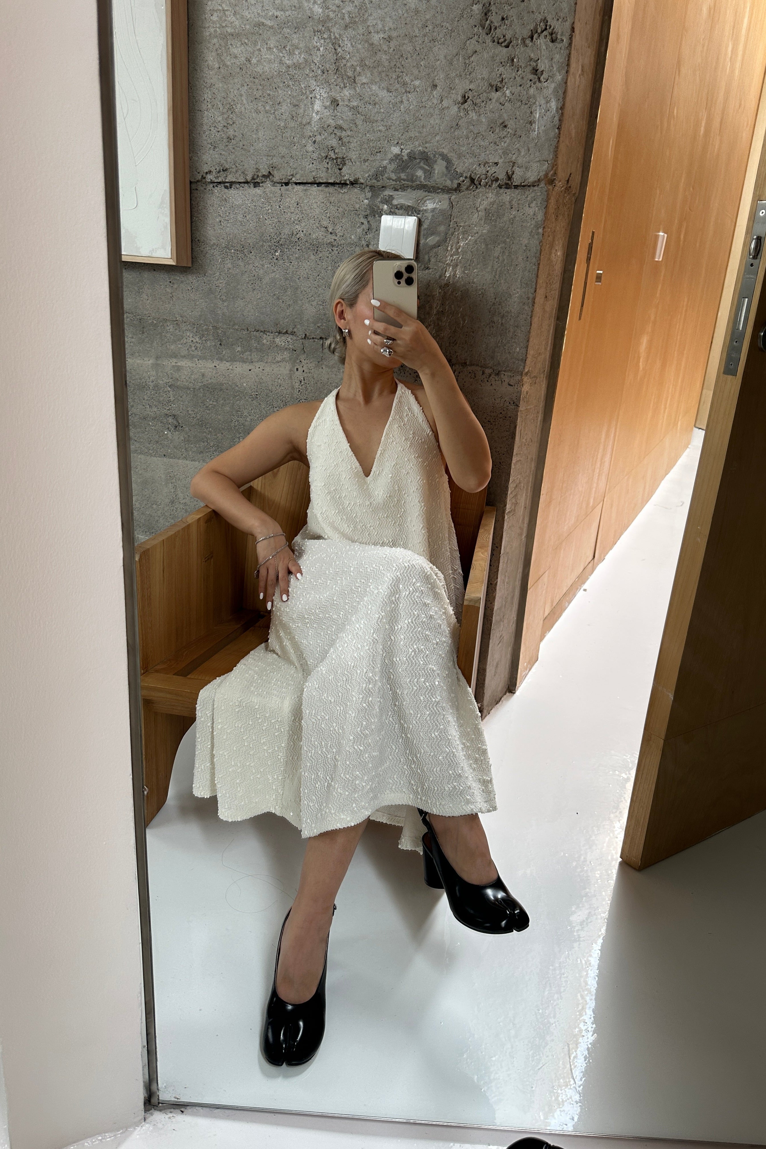 Woman in a white a-line shapeless draped dress with a scooped v-neck that flows with movement, featuring subtle textural details and fine sequins. Perfect for beach days or Summer outings.