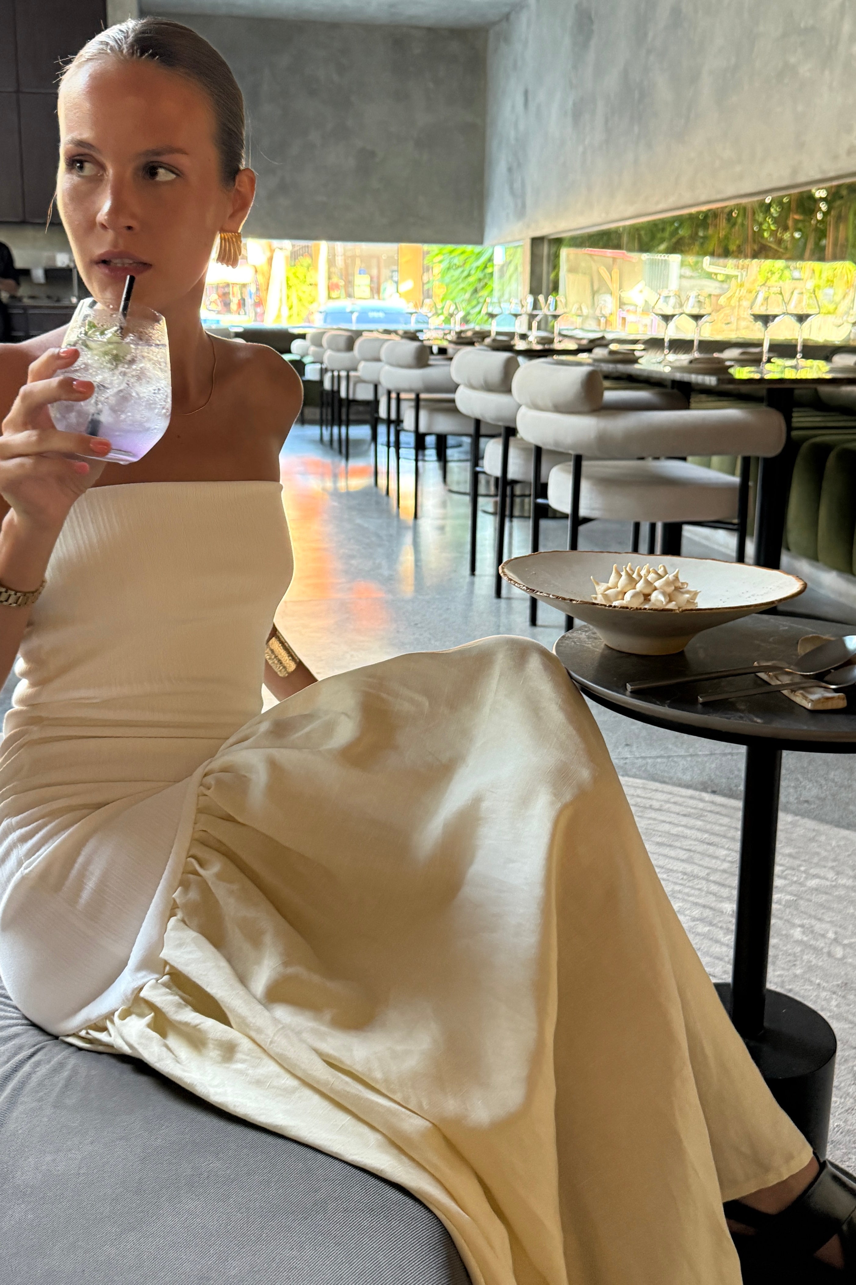 Woman in strapless white maxi dress with asymmetric artfully gathered lemon skirt. Top flatters the figure and skirt adds flow with every movement. Perfect for beach outings and summer soirées.
