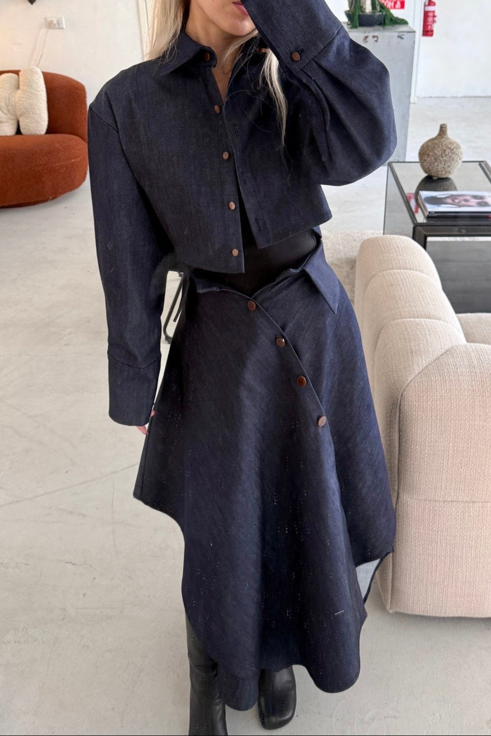 Woman in denim handkerchief hem long skirt with collar waist band detail. Styled with matching boxy cropped jacket.