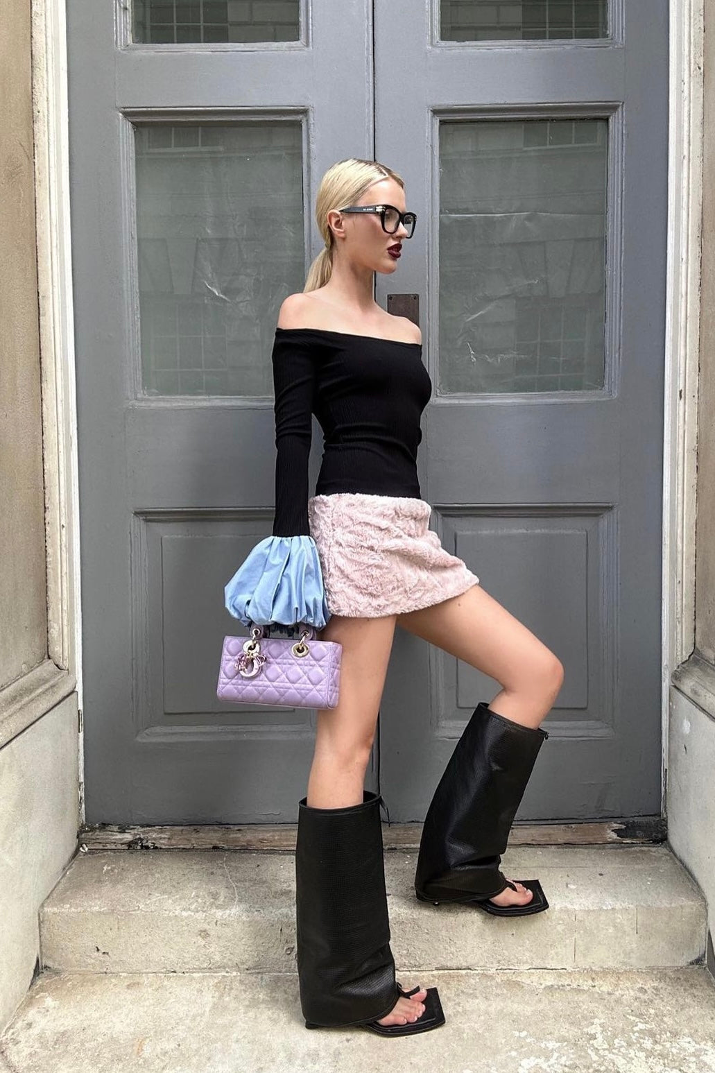 Woman in black long sleeve rib knit top with round neckline and blue balloon details on cuffs. Styled off the shoulder.