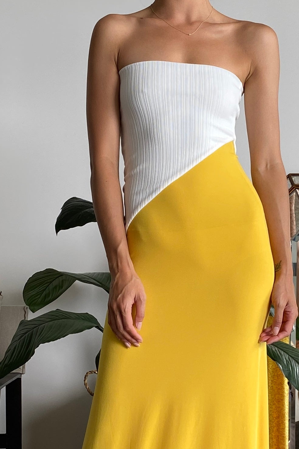 Woman in strapless maxi dress with white top and yellow skirt.