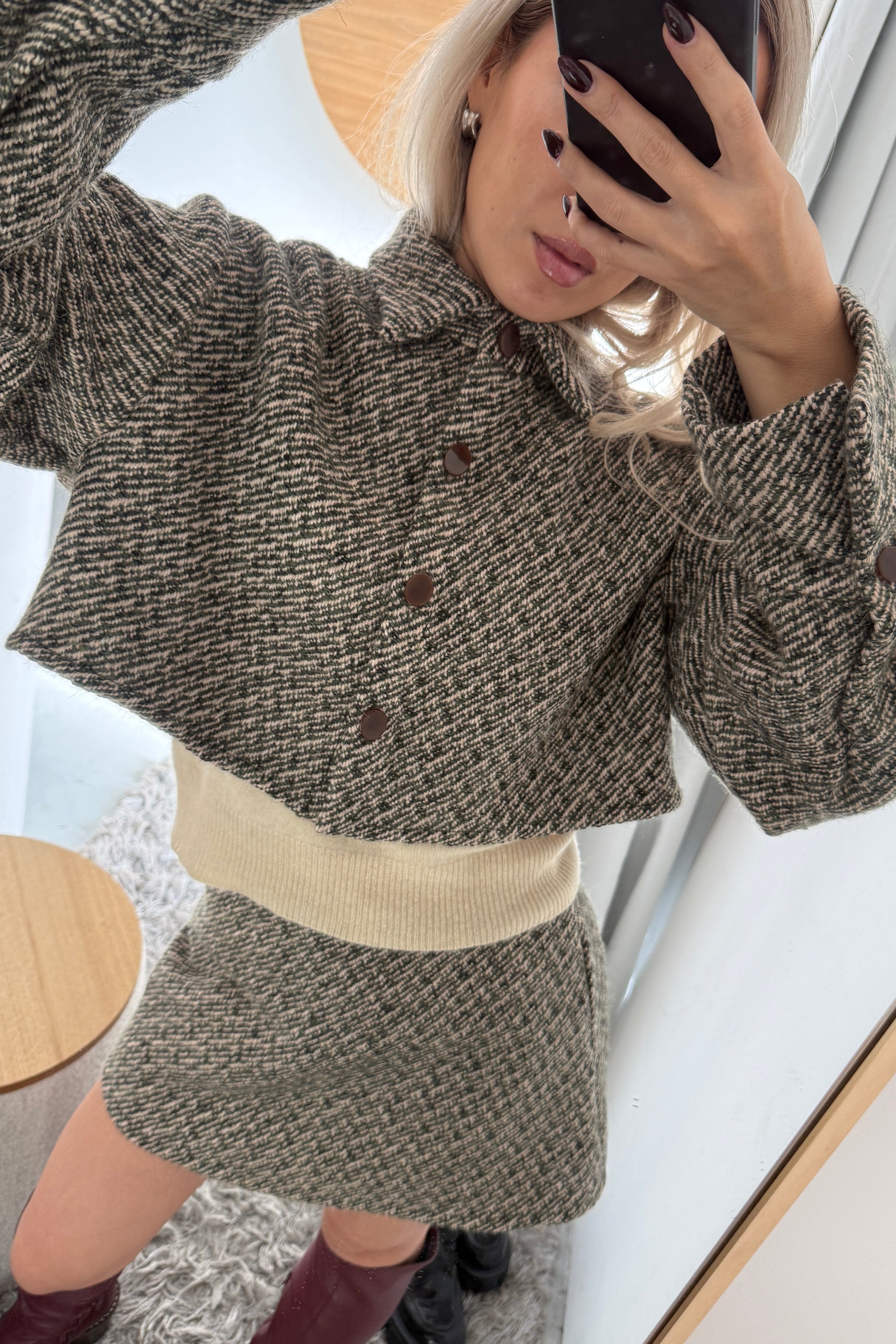 Woman in olive wool bouclé mini skirt with matching boxy fit cropped jacket.