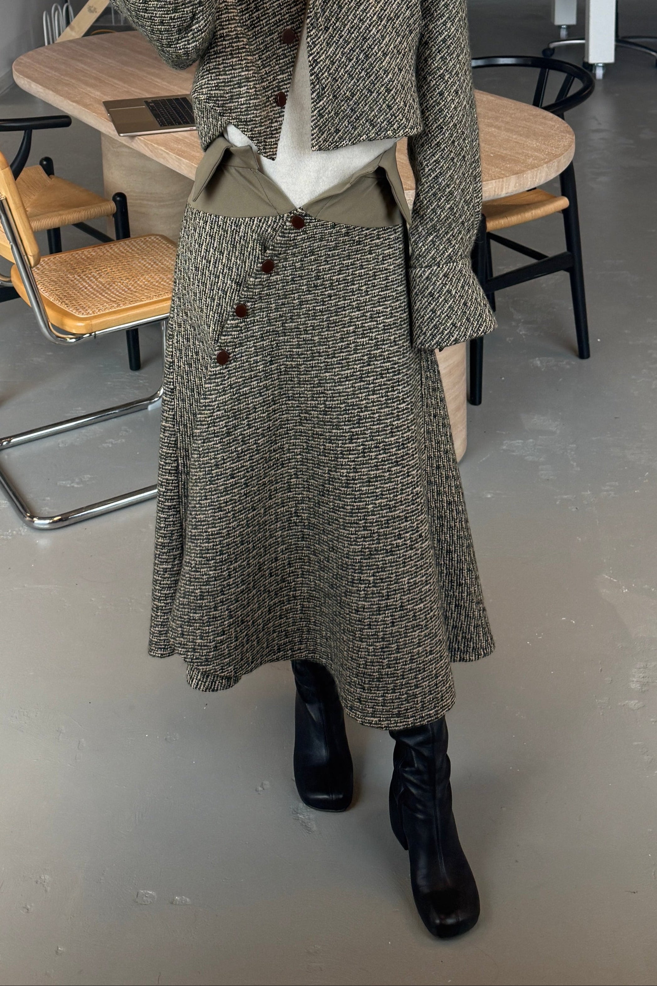 Woman in olive Japanese wool bouclé midi handkerchief hem skirt with button front closure. Styled with matching jacket.