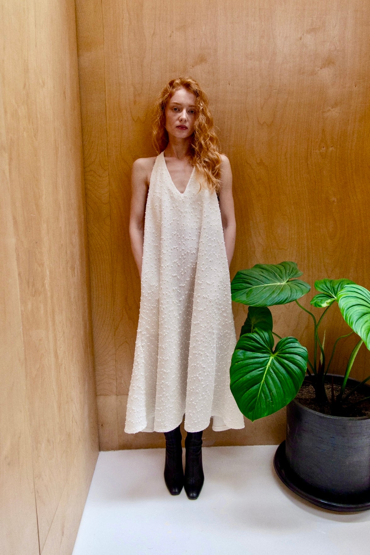 Woman in a white a-line shapeless draped dress with a scooped v-neck, featuring subtle textural details and fine sequins, including hidden side pockets. Perfect for beach days or Summer outings.