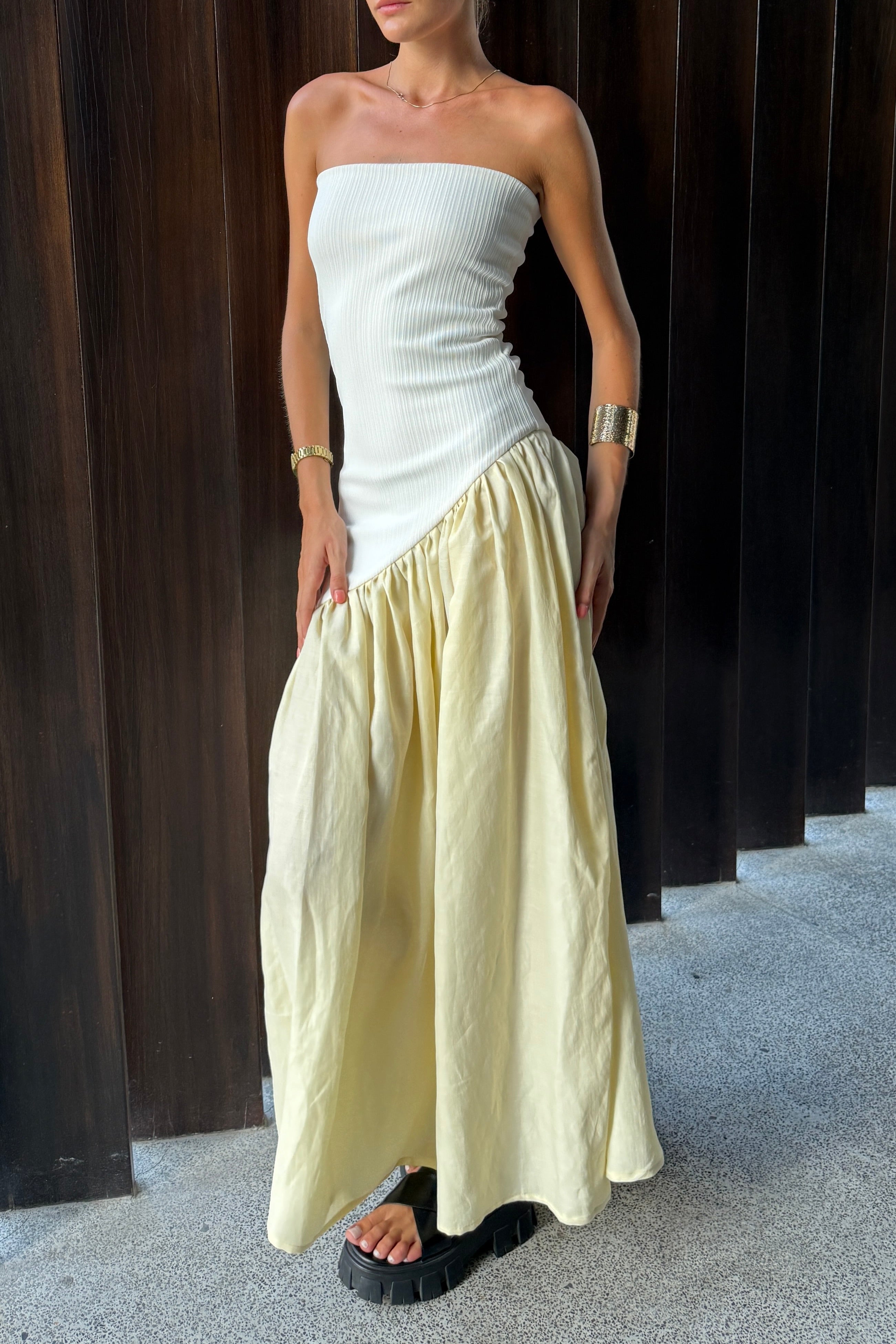 Woman in strapless white maxi dress with asymmetric artfully gathered lemon skirt. Top flatters the figure and skirt adds flow with every movement. Perfect for beach outings and summer soirées.
