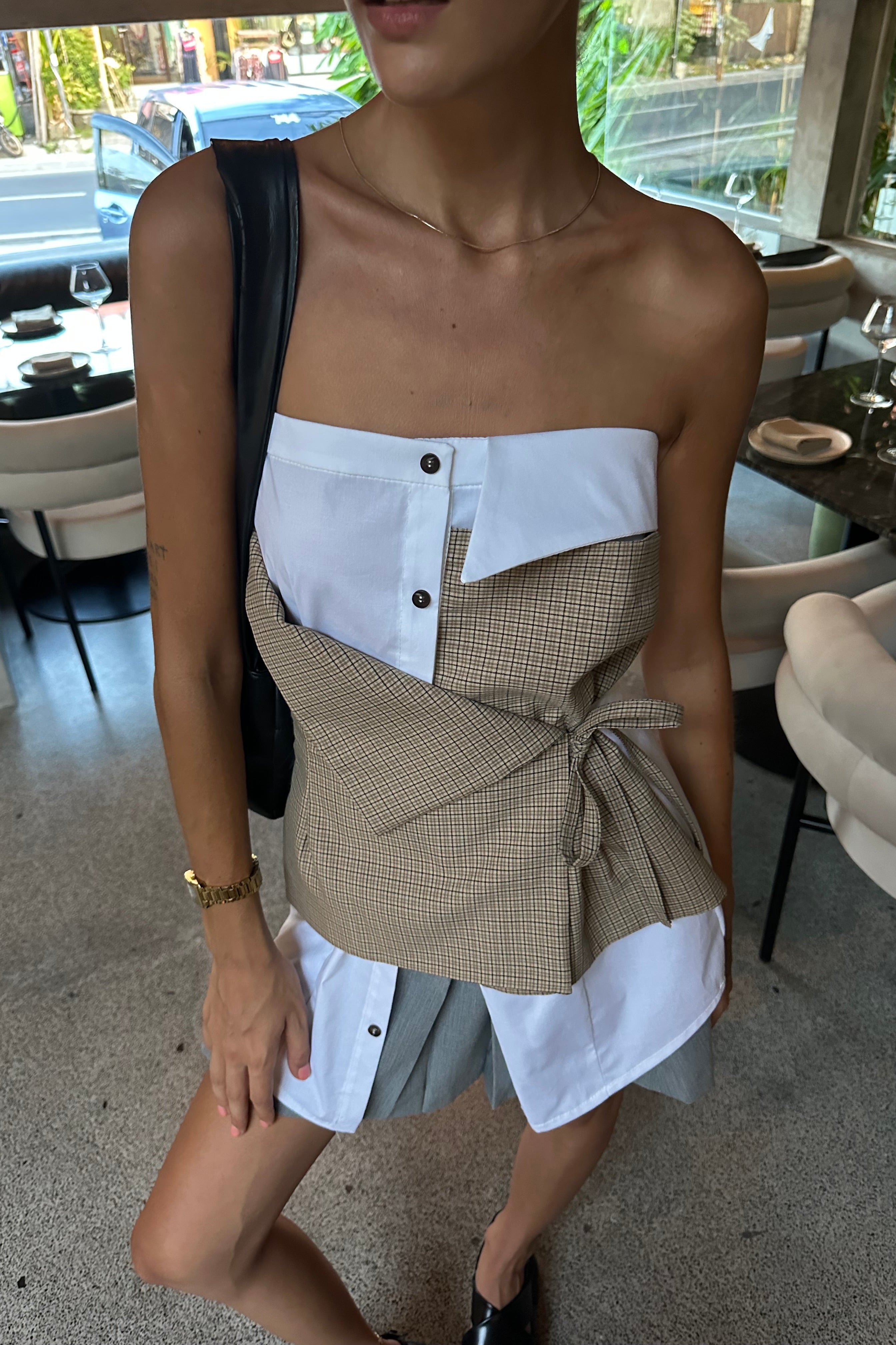 Woman in white strapless top with elements of traditional shirting. Layered beige check asymmetric tie front detail. Deconstructed look.
