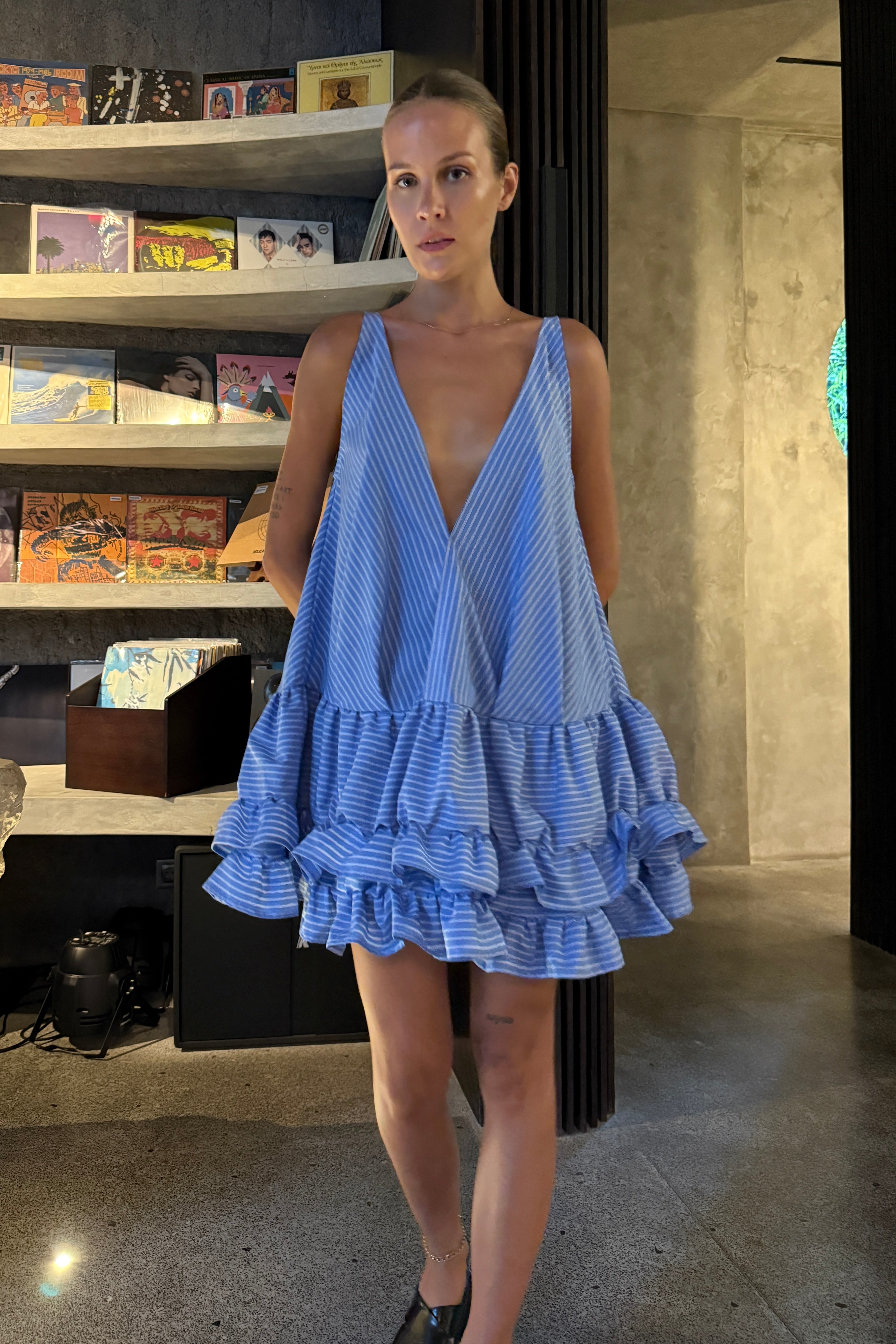 Woman in a baby blue striped deep v-neck mini ruffled dress. The perfect beach cover up or casual summer dress.