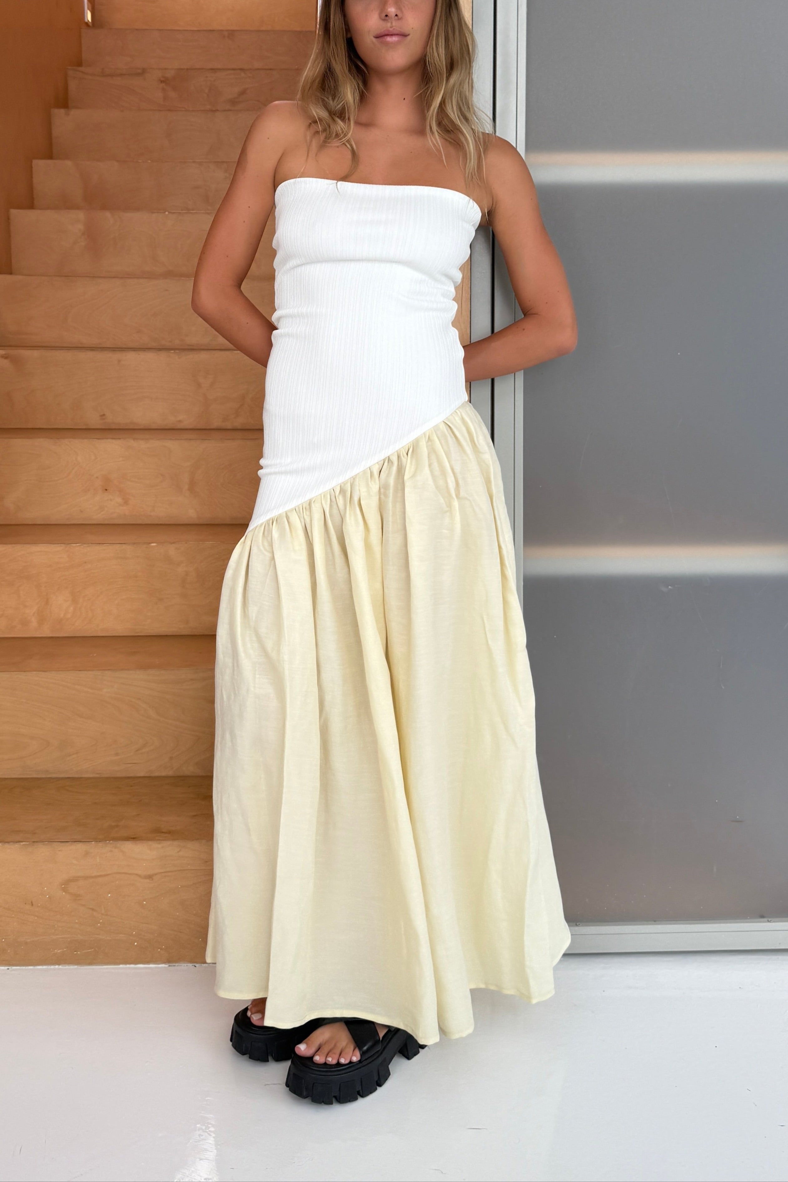 Woman in strapless white maxi dress with asymmetric artfully gathered lemon skirt. Top flatters the figure and skirt adds flow with every movement. Perfect for beach outings and summer soirées.
