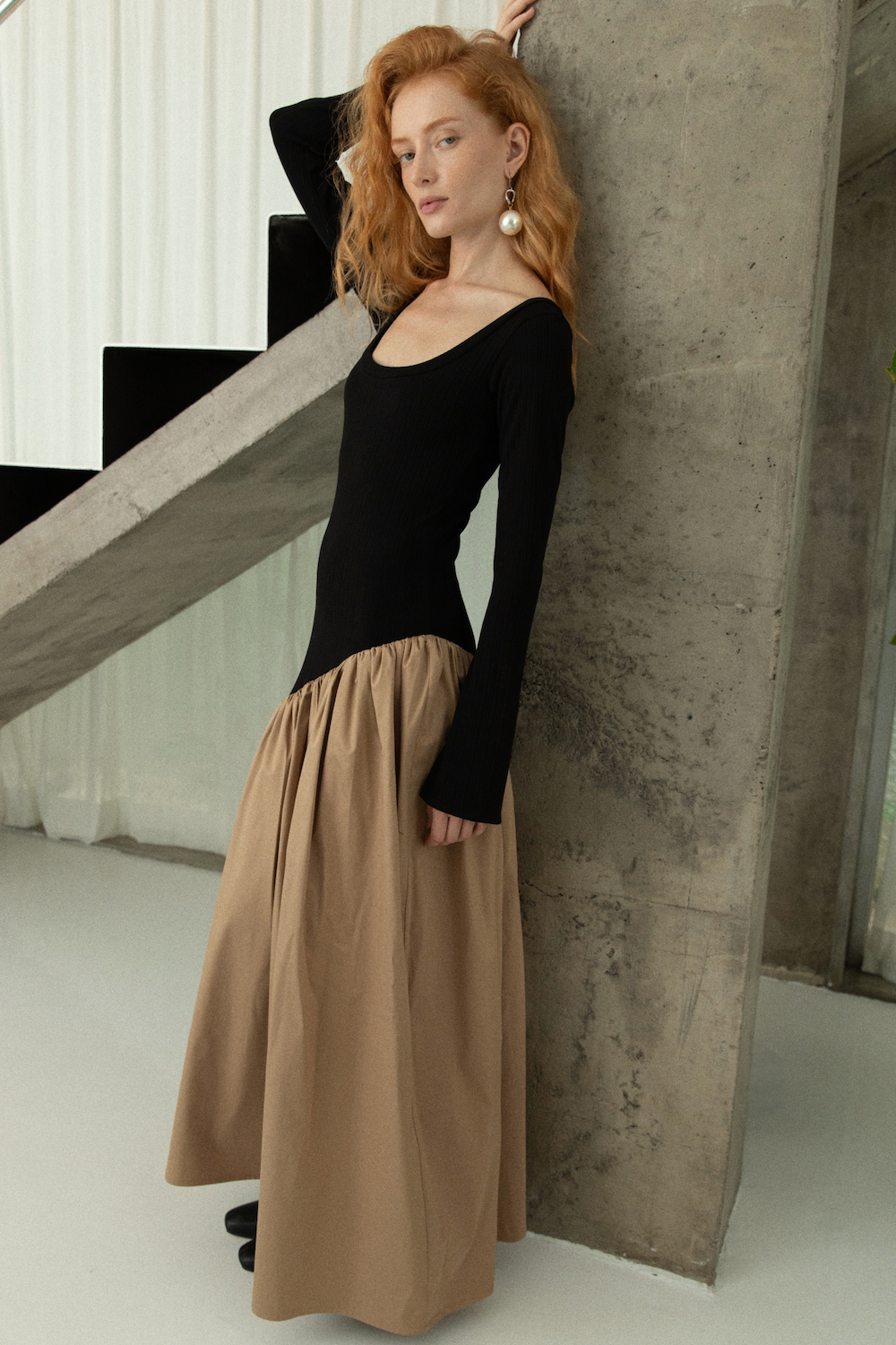 Woman in long sleeve dress, with extra long sleeves, scooped neckline, and artfully gathered asymmetric beige skirt. Top flatters the figure whilst the skirt flows with every movement. Can be dressed up or down.