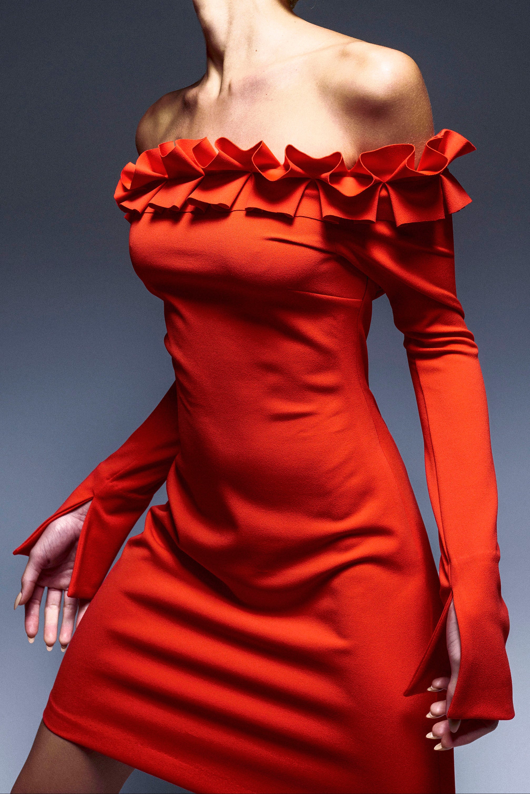 Woman in long sleeve, off the shoulder mini dress, ruffle detail along the neckline. Occasion wear essential.