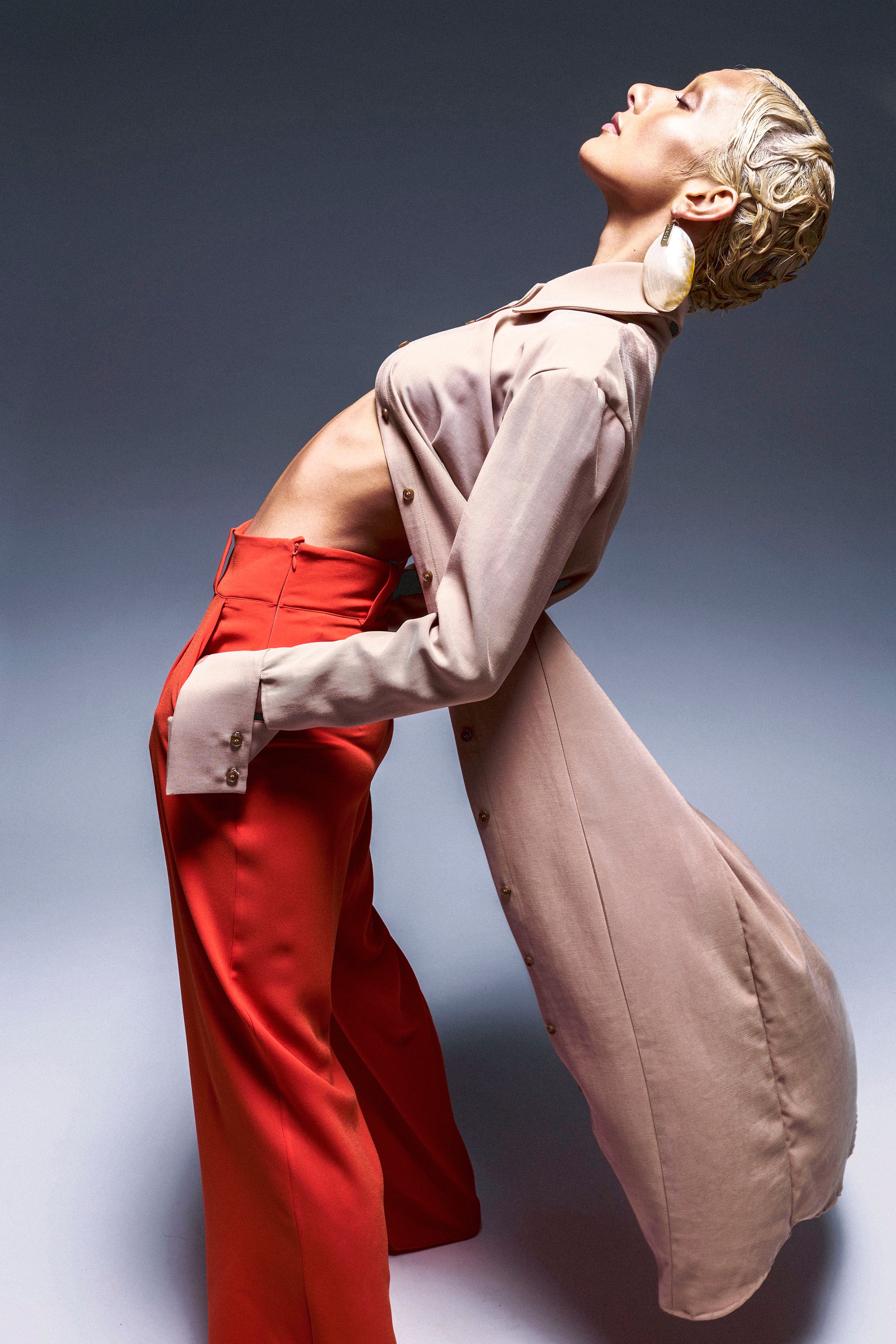 Woman in wide leg orange pants with side pockets and side zip closure. Styled with beige shirt.