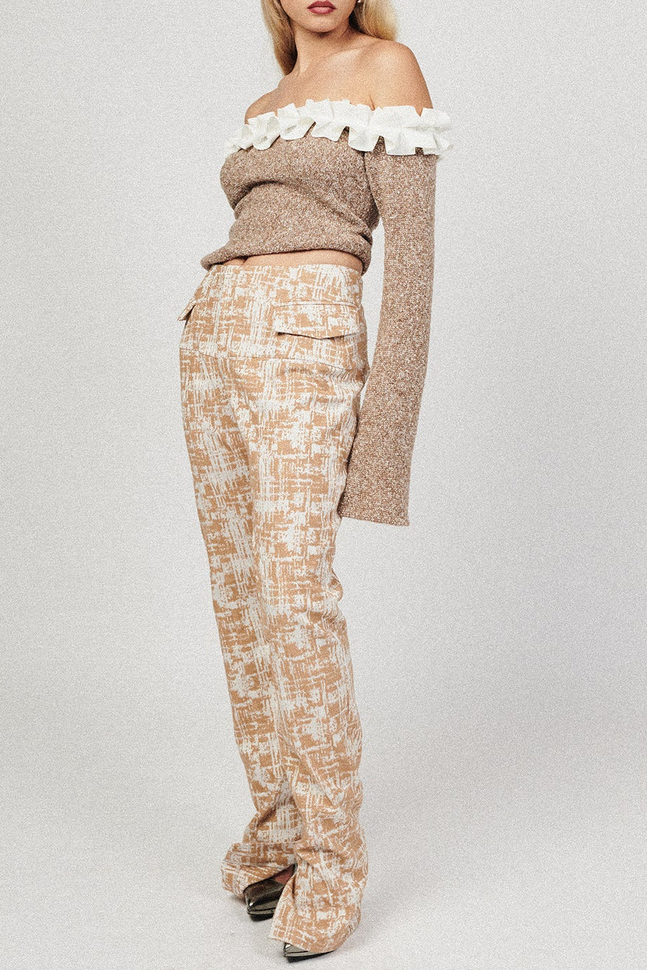 Woman in textured brown off shoulder top. Featuring white ruffle detail along the neckline.