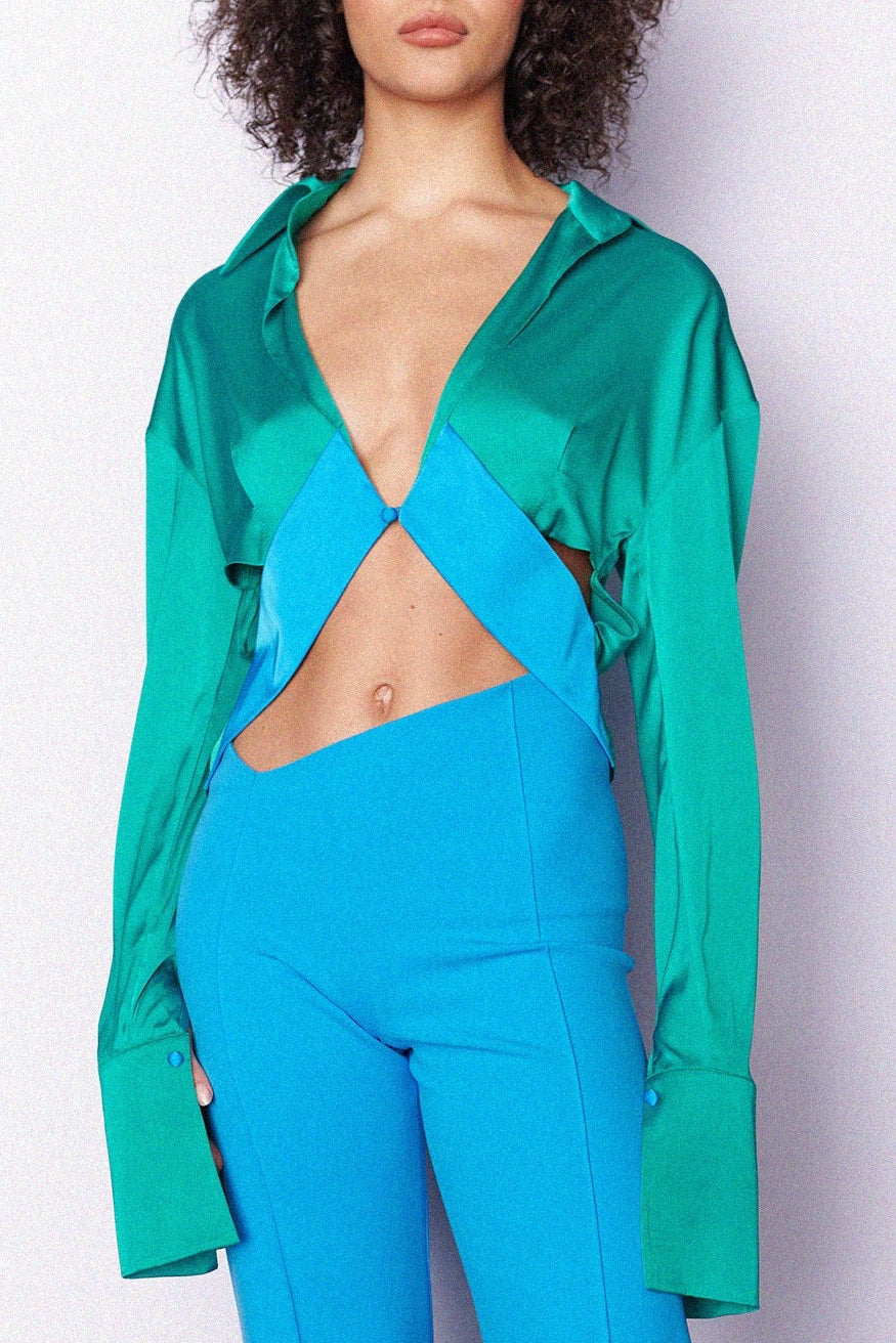 Woman in green and blue long sleeve, singular button down, cropped shirt. Styled with matching blue trousers. Perfect for holidays/vacation.