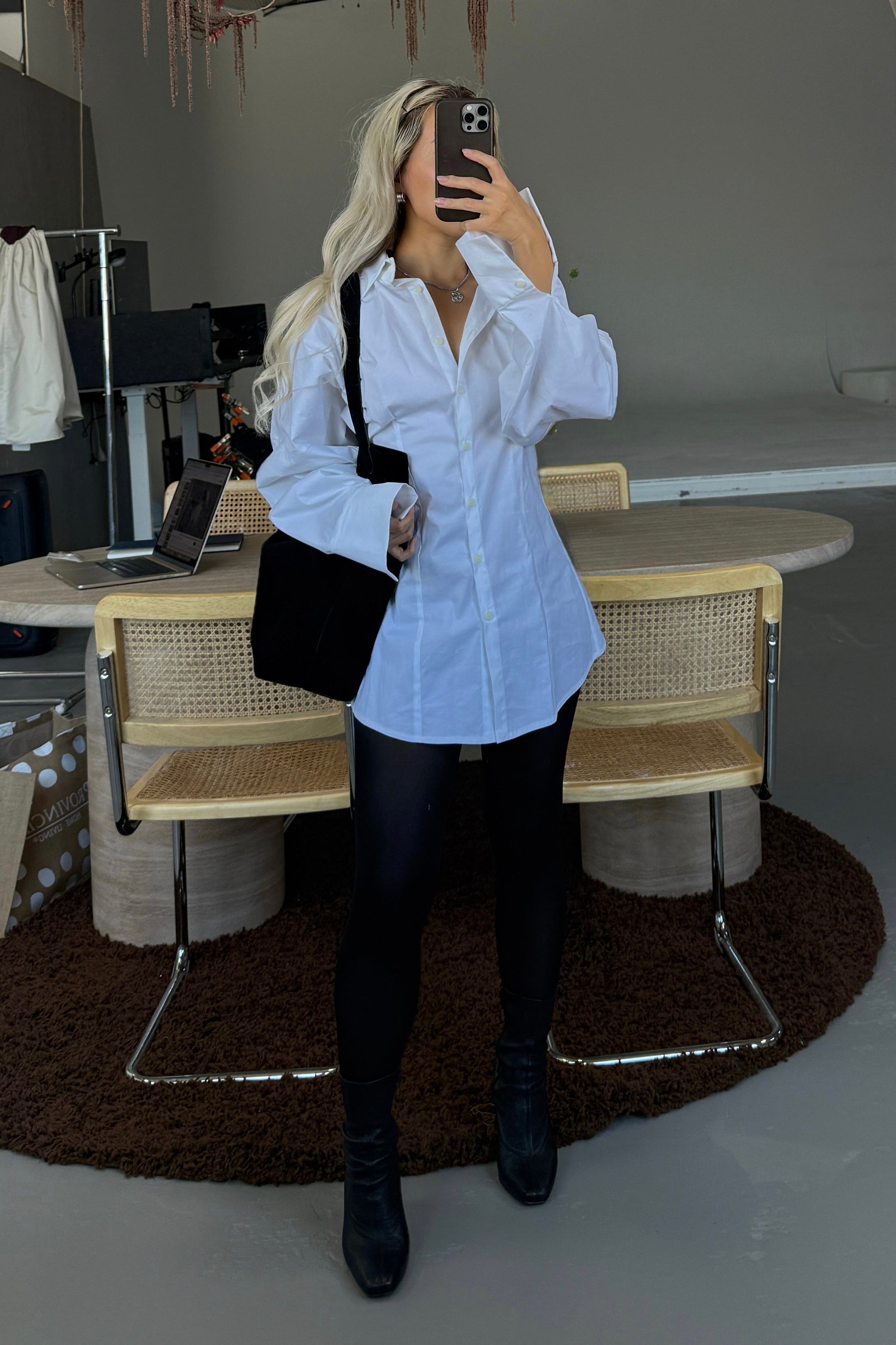 Woman in white volume sleeve shirt dress. Styled over black trousers.
