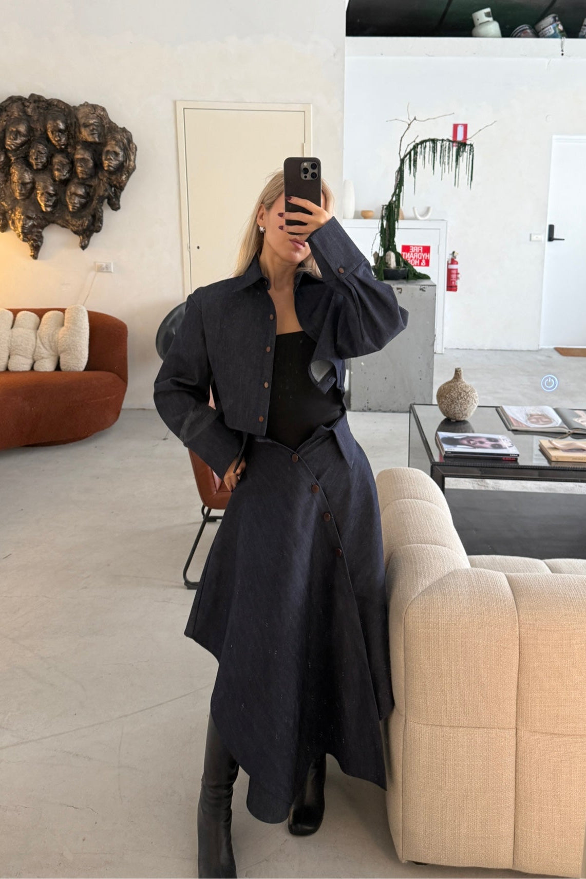 Woman in denim handkerchief hem long skirt with collar waist band detail. Styled with matching boxy cropped jacket.