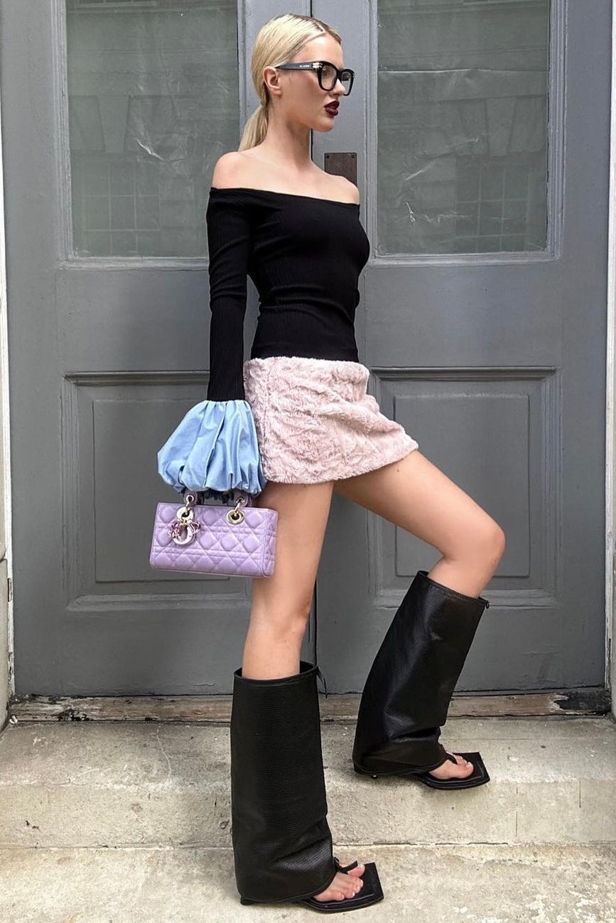 Woman in black long sleeve rib knit top with round neckline and blue balloon details on cuffs. Styled off the shoulder.