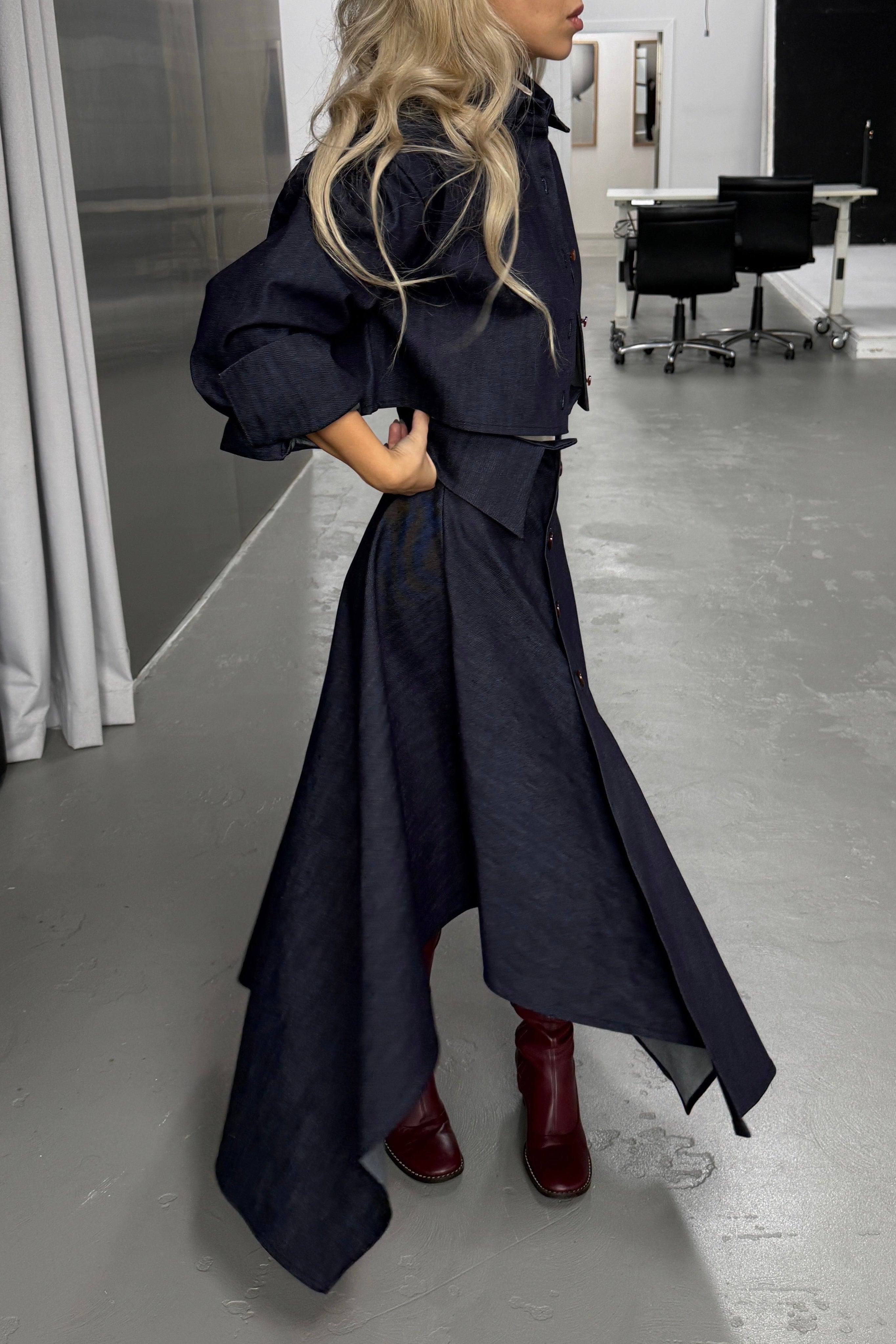 Woman in denim handkerchief hem long skirt with collar waist band detail. Styled with matching boxy cropped jacket.