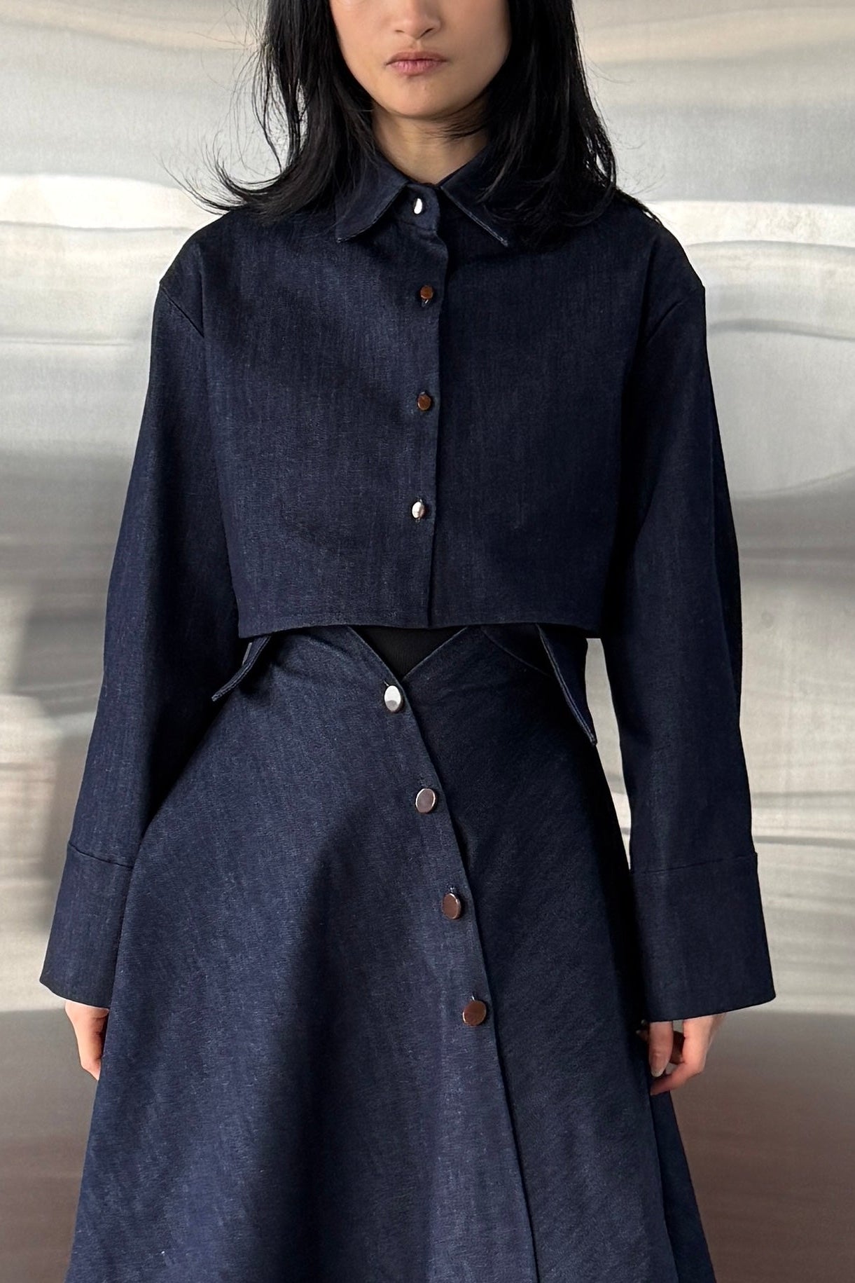 Woman in denim handkerchief hem long skirt with collar waist band detail. Styled with matching boxy cropped jacket.