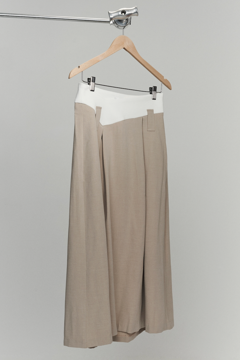 Flat lay of long skirt with box pleats and dipped waistband. Beige and white colourway. 