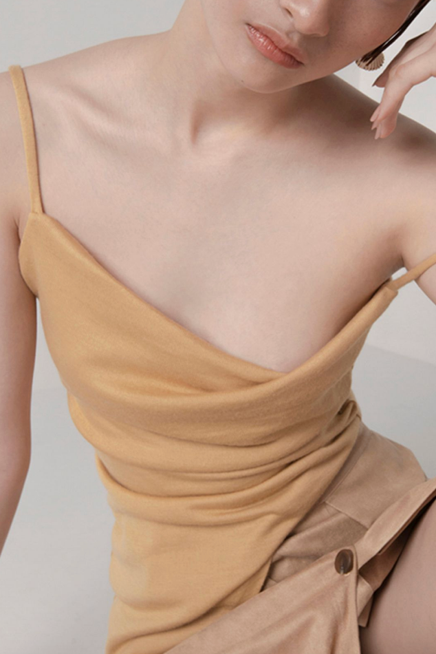 Woman in custard cowl neck asymmetric hem top. 